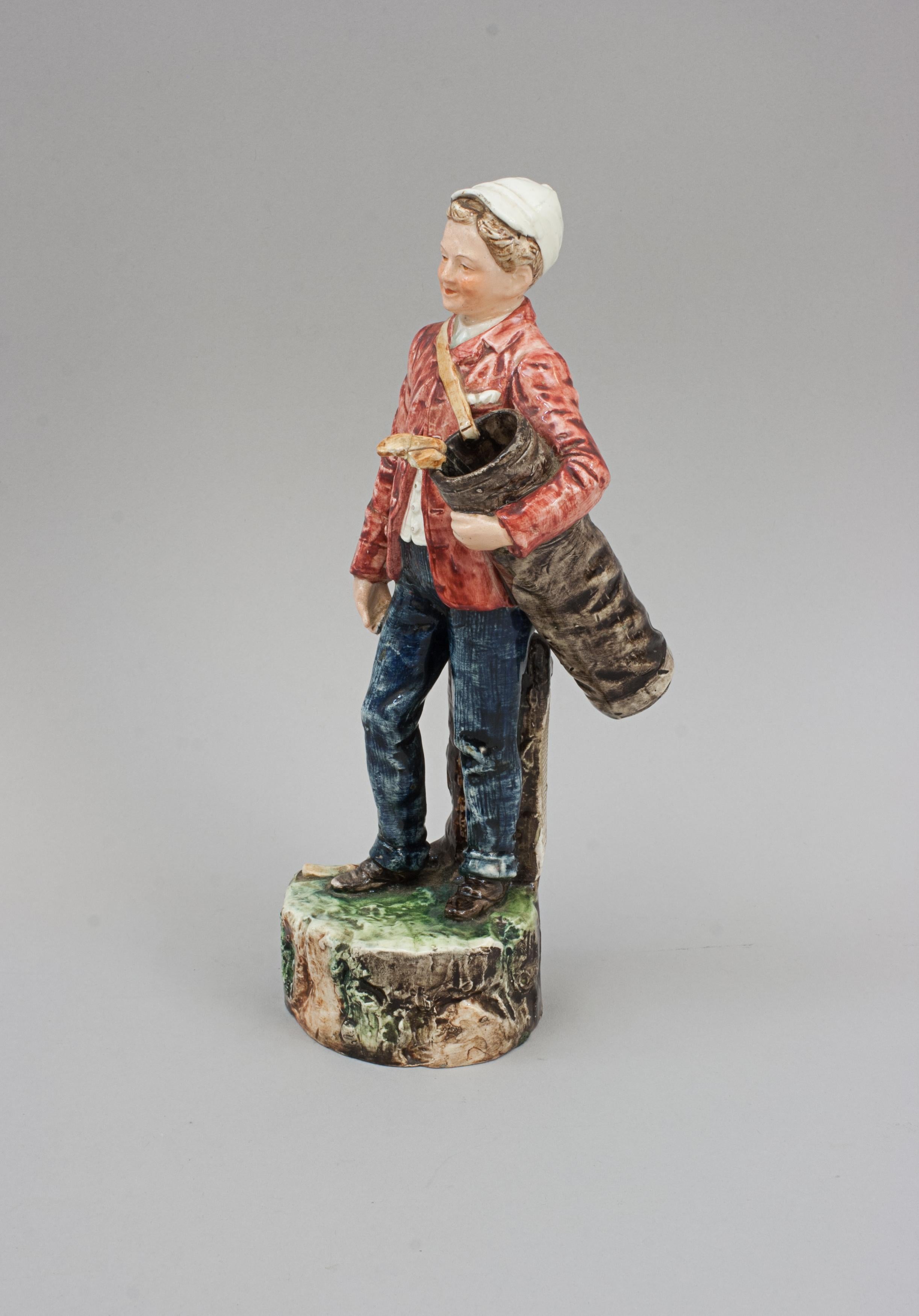 Golf Caddy Match Holder & Striker.
Eine Keramik-Golffigur in Form eines jungen Caddies, der eine Golftasche mit zwei Schlägern hält. Die Golftasche dient zur Aufbewahrung der Streichhölzer und der Baumstumpf hat eine raue Seite, auf der die