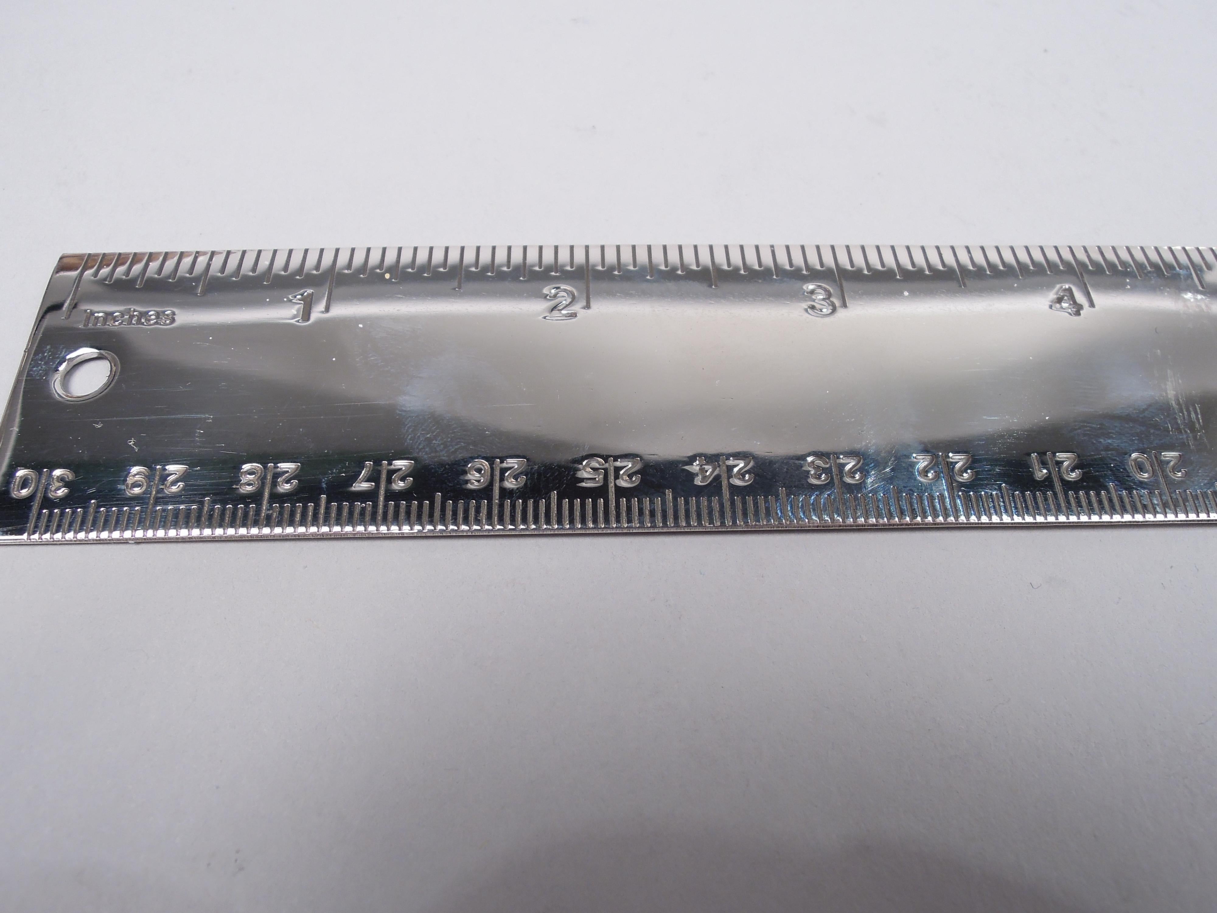 Novelty sterling silver desk accessory. In form and with dimensions of a 12-inch ruler engraved on one edge and 30 centimeters on the other. Back plain. Stylish and useful with small cutout circle for hanging. Marked “Tiffany & Co / Sterling”.