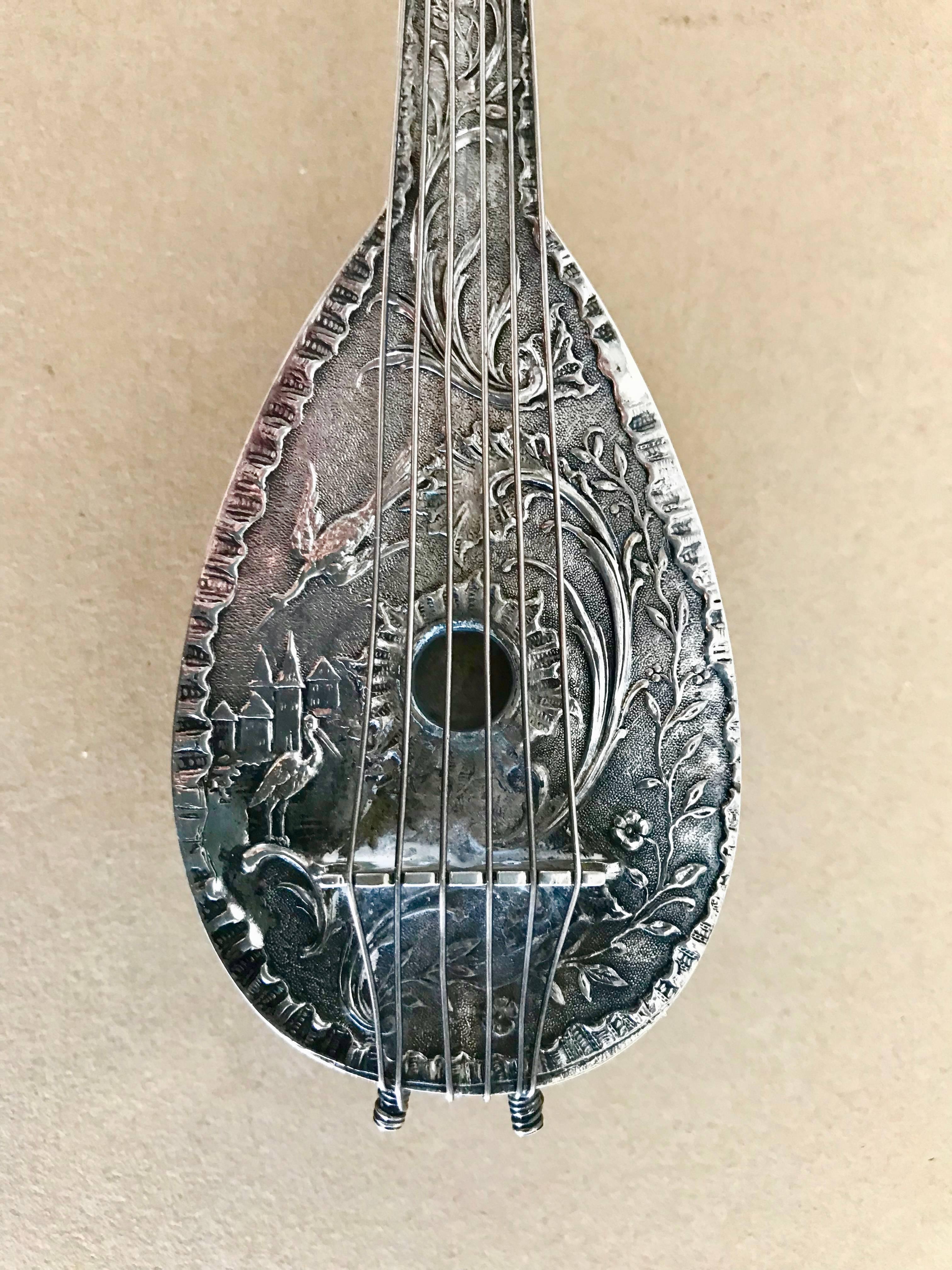 Dutch silver flask in the form of a mandolin with intricate Baroque style decoration, including cranes and a castle among floral arabesques on the front. The reverse depicting a charming scene influenced by Dutch old master genre paintings of two