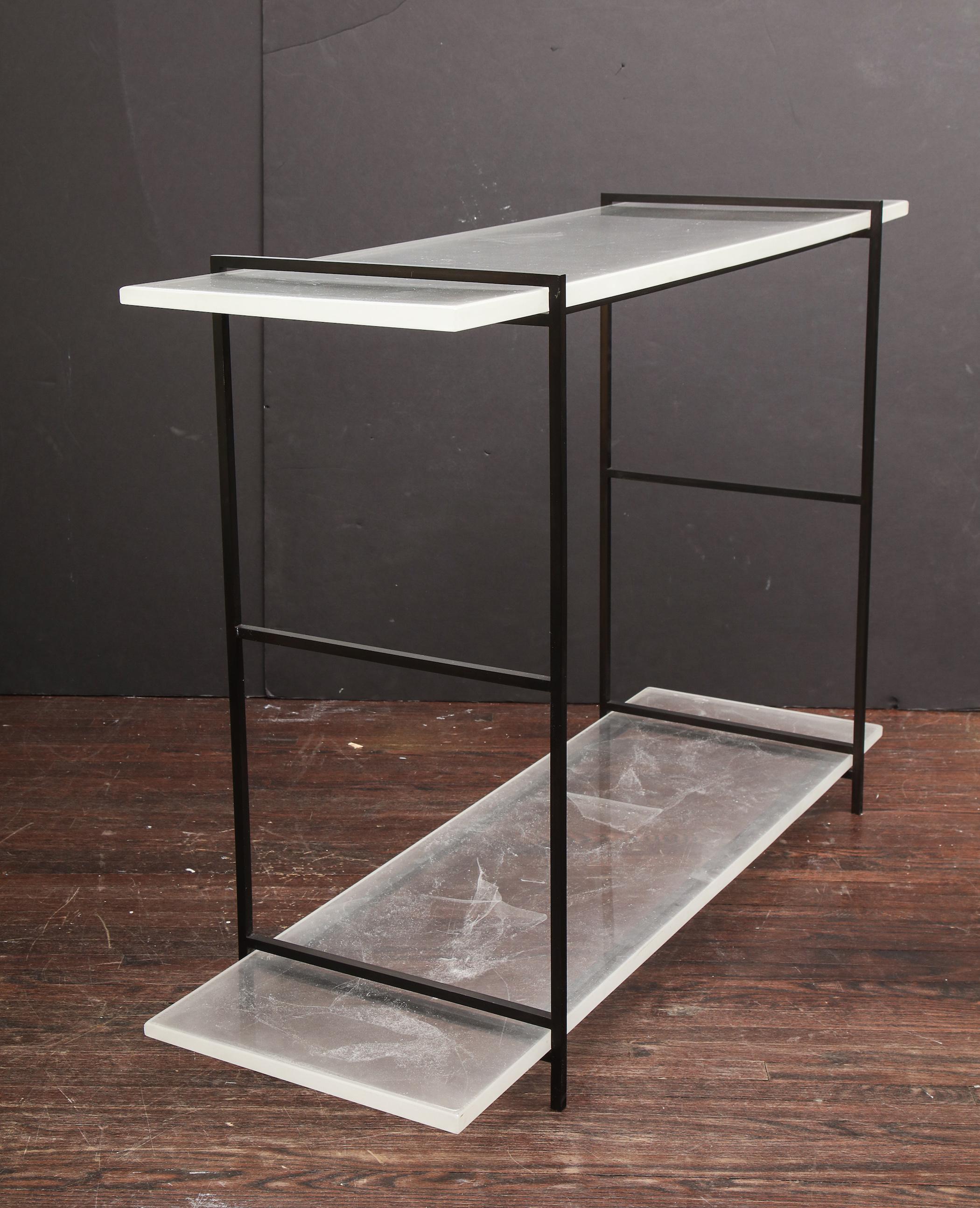 Novelty stardust glass console table with solid black metal legs. Each acrylic surfaces are infused with unique stardust-like texture that makes a contrast to the simple smooth black metal legs. The top surface is at 33-1/2