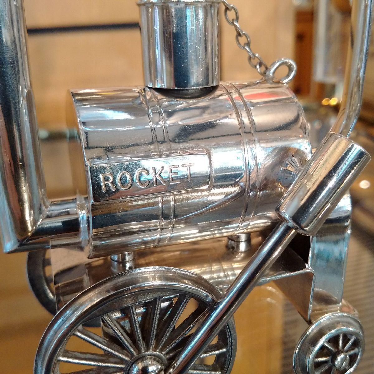 P H Vogel and Co, Birmingham

A highly unusual and amusing, silver plated brandy warmer in the form of Stephenson’s Rocket, the frame for the glass sitting over the ‘boiler’ with engraved ‘ROCKET’ to the side, which contains the fuel, and a wick,