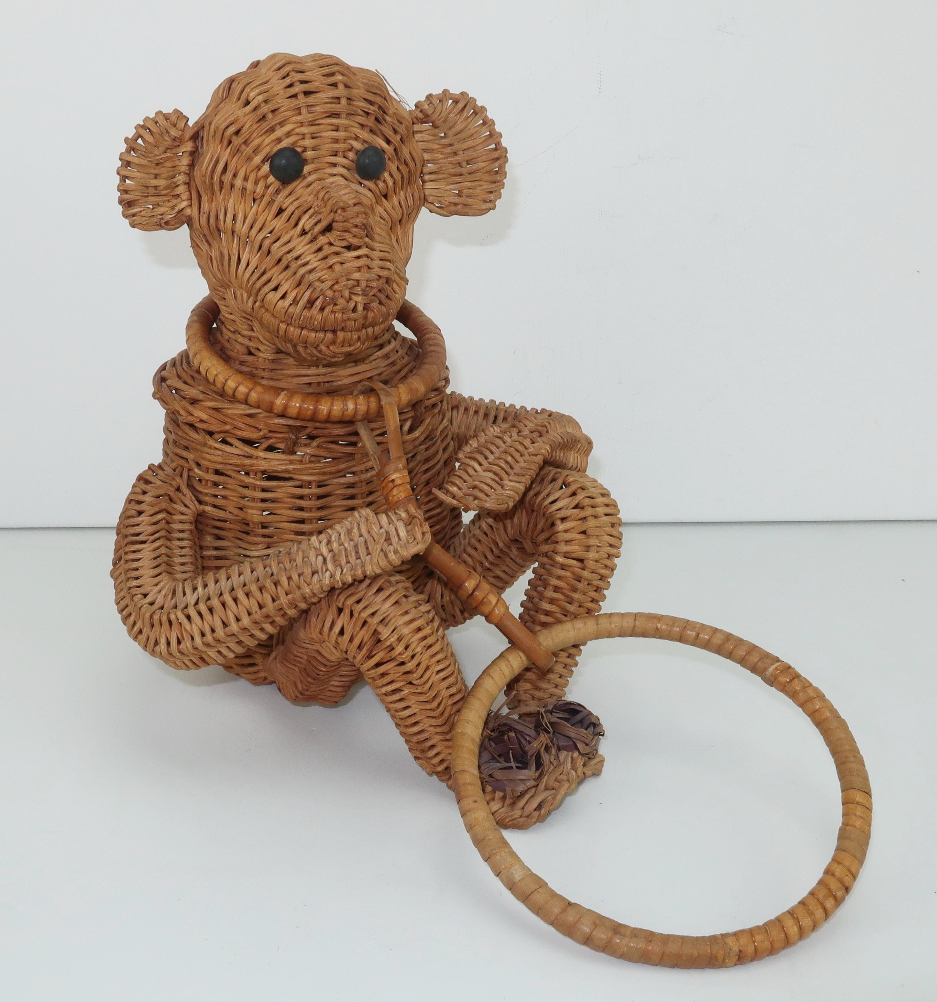 Adorable 1950's wicker monkey handbag with button eyes and raffia rosettes on the toes.  He opens at the back with an elasticized closure and the wristlet style handle masquerades as a leash to keep him by your side.  The interior compartment is