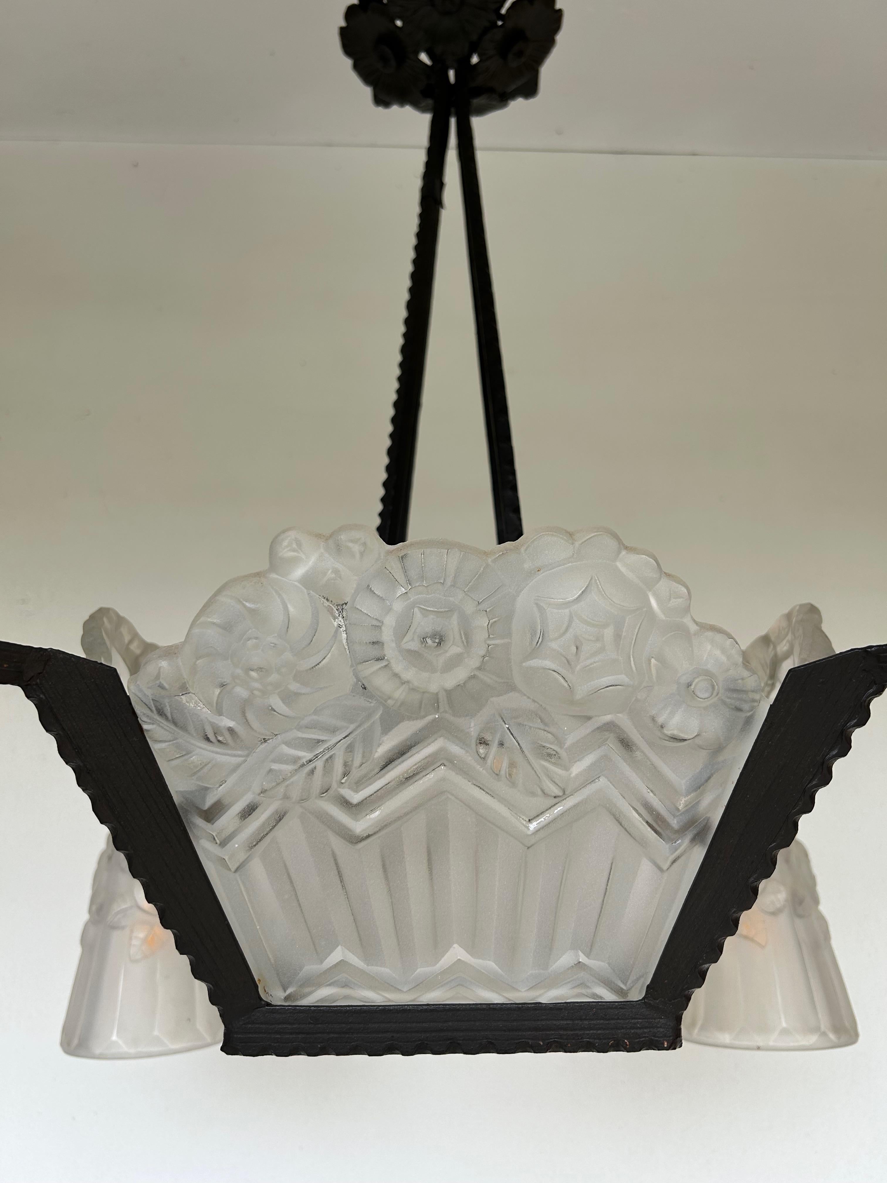 Lampadario Art Deco Noverdy.
Struttura in ferro battuto con patina nera.
4 lastre di vetro verticali e una lastra centrale.
4 tulipani con decorazioni geometriche e floreali.
Attacco per lampadina a baionetta B22 elettrificato (disponibile su Amazon