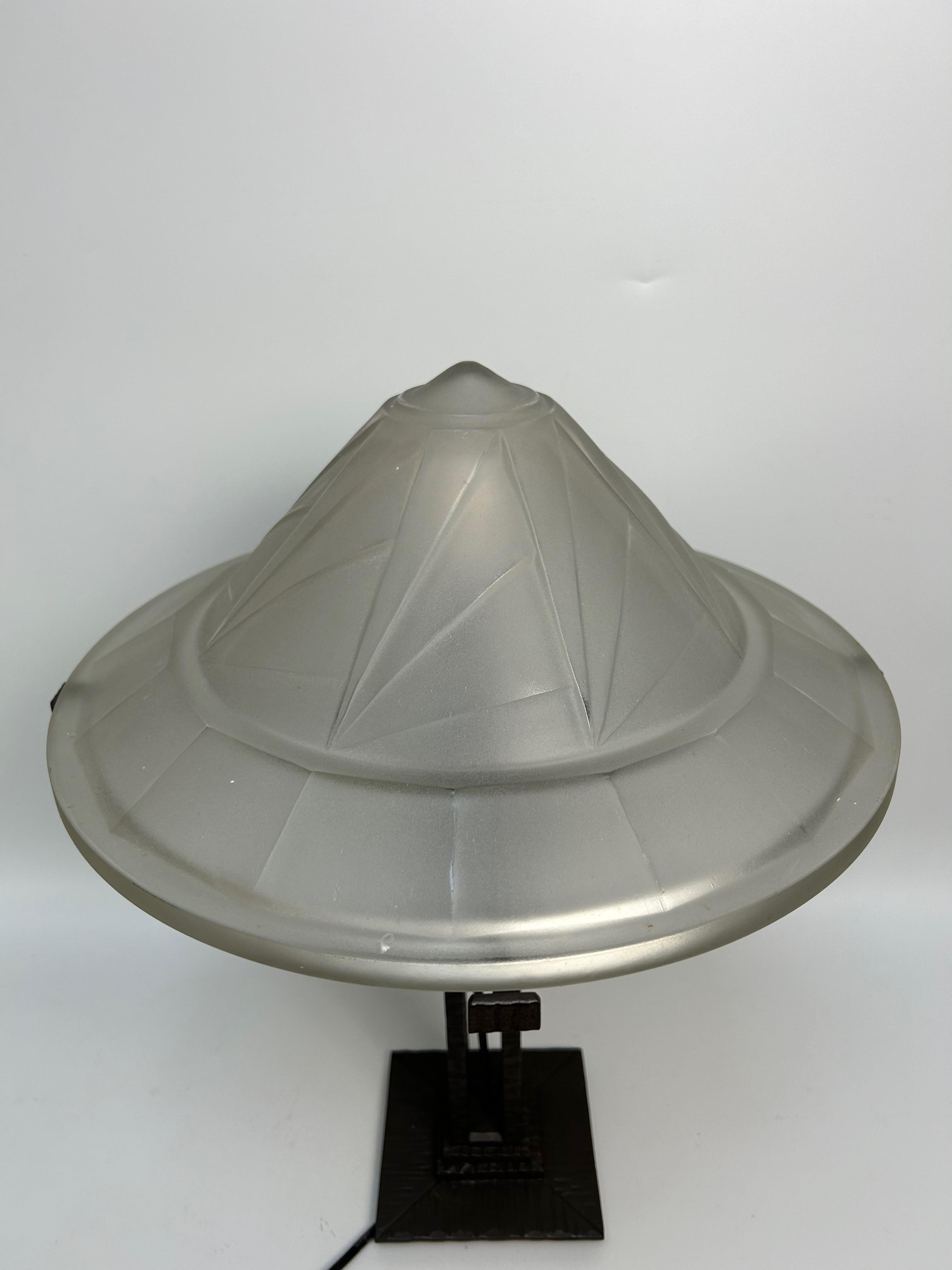 Art Deco lamp circa 1930.
Wrought iron base with black patina.
Pressed molded glass bowl with geometric decoration signed Noverdy France.

Height: 46 cm
Shell diameter: 35 cm
Weight: 5kg

Very little information on Jean Noverdy, master glassmaker