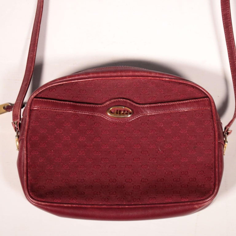 Gucci shoulder bag, probably from 1980s.
The purse is burgundy both in the leather parts and in the fabric ones, on which the brand logo is printed 
