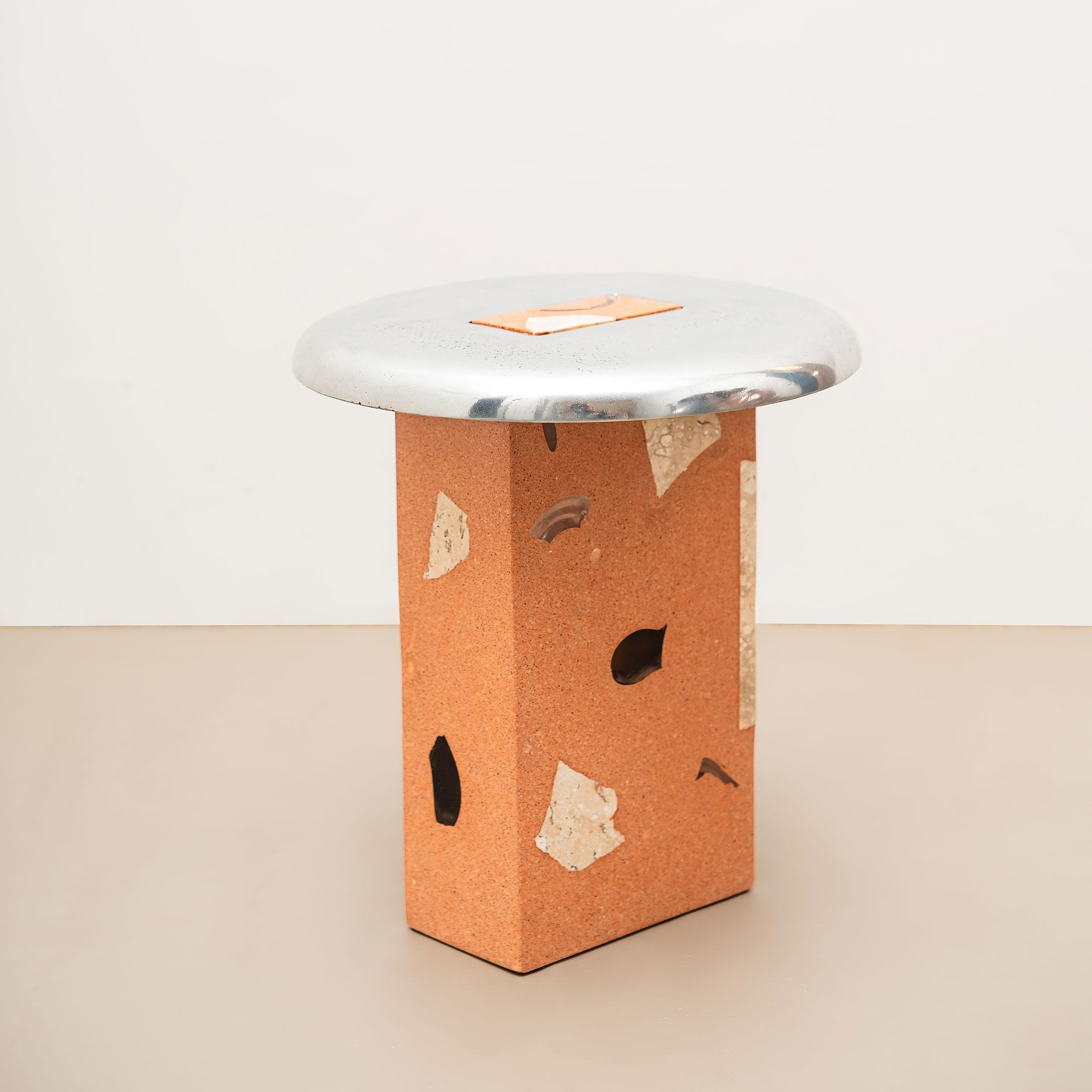 Säule aus zerkleinertem, recyceltem Keramikziegel, mit Glas und beigefarbenem Bahia-Marmor. Platte aus wiederverwertetem Aluminiumguss mit polierter Oberfläche. 

-
NU ist eine Kollektion, die dem Wesen der Materialien gewidmet ist, wobei wir