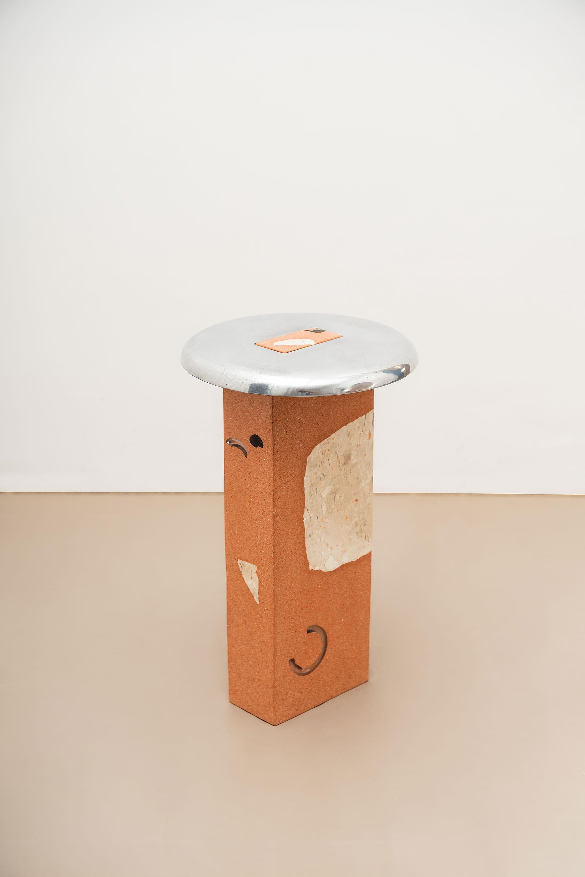 Colonne fabriquée à partir de briques céramiques recyclées concassées, avec des agrégats de verre et de marbre beige de Bahia. Plateau en fonte d'aluminium recyclé avec finition polie. 

-
NU est une collection dédiée à l'essence des matériaux, où