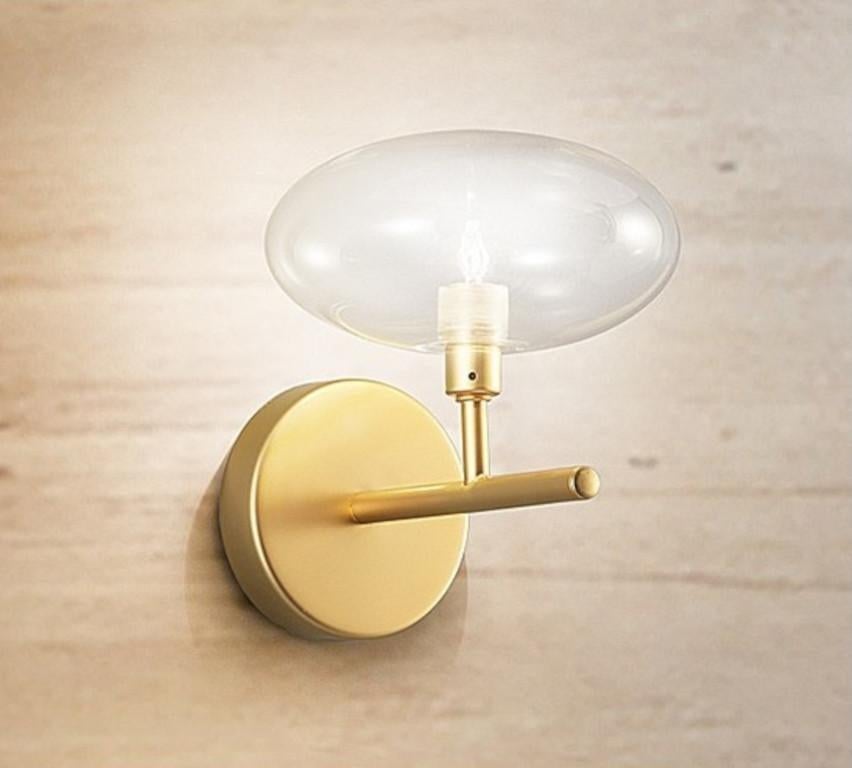 Moderne italienische Wandleuchte mit klarem Glasschirm auf einem mattgoldenen Metallrahmen / Made in Italy by Fabio Ltd
Höhe: 10 Zoll / Breite: 6 Zoll / Tiefe: 7 Zoll 
1 Leuchte / Typ G9 / max 25W
Nur auf Bestellung / Dieser Artikel wird aus Italien
