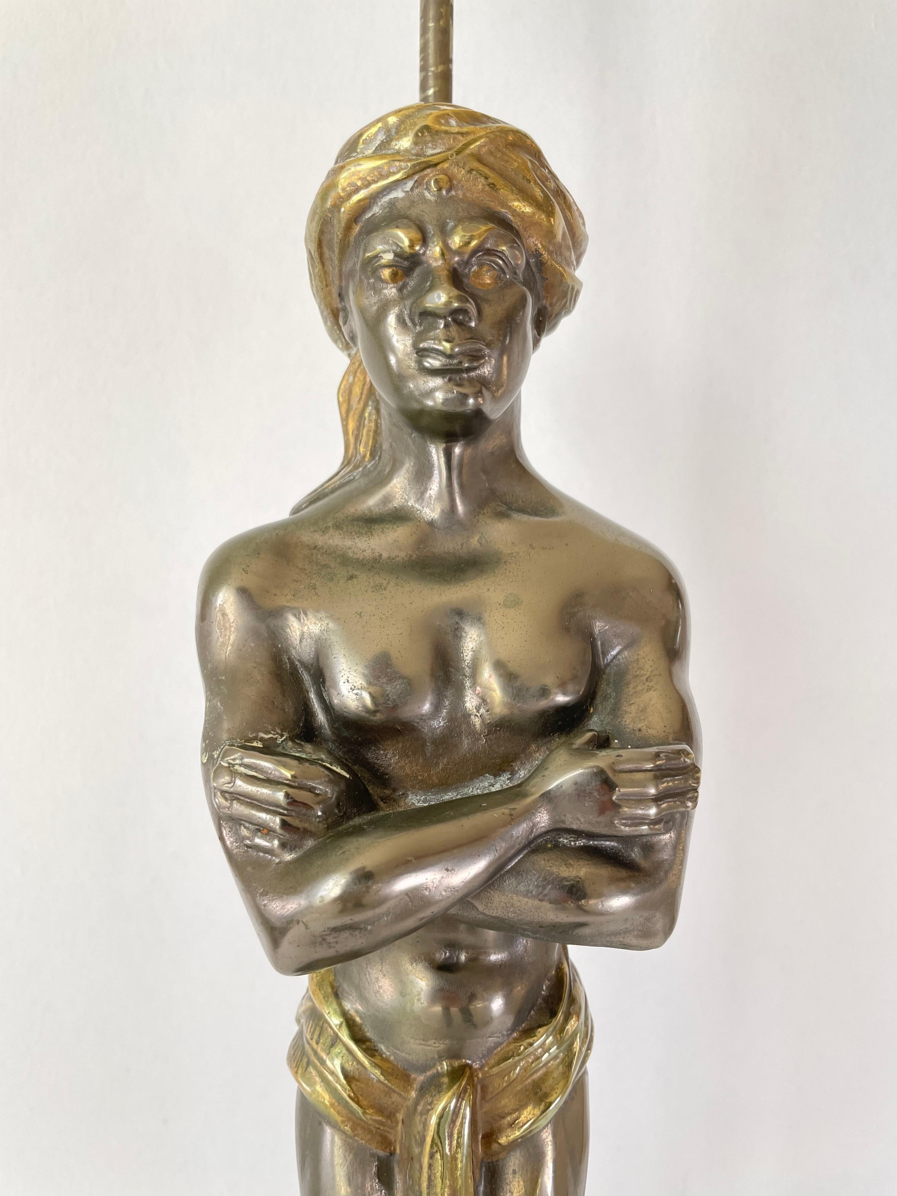 Lampe en bronze doré et argent représentant un Nubien avec les bras croisés, un turban sur la tête et une serviette autour de la taille. La base est en marbre et l'électricité a été refaite pour le standard américain. L'abat-jour n'est pas fourni.