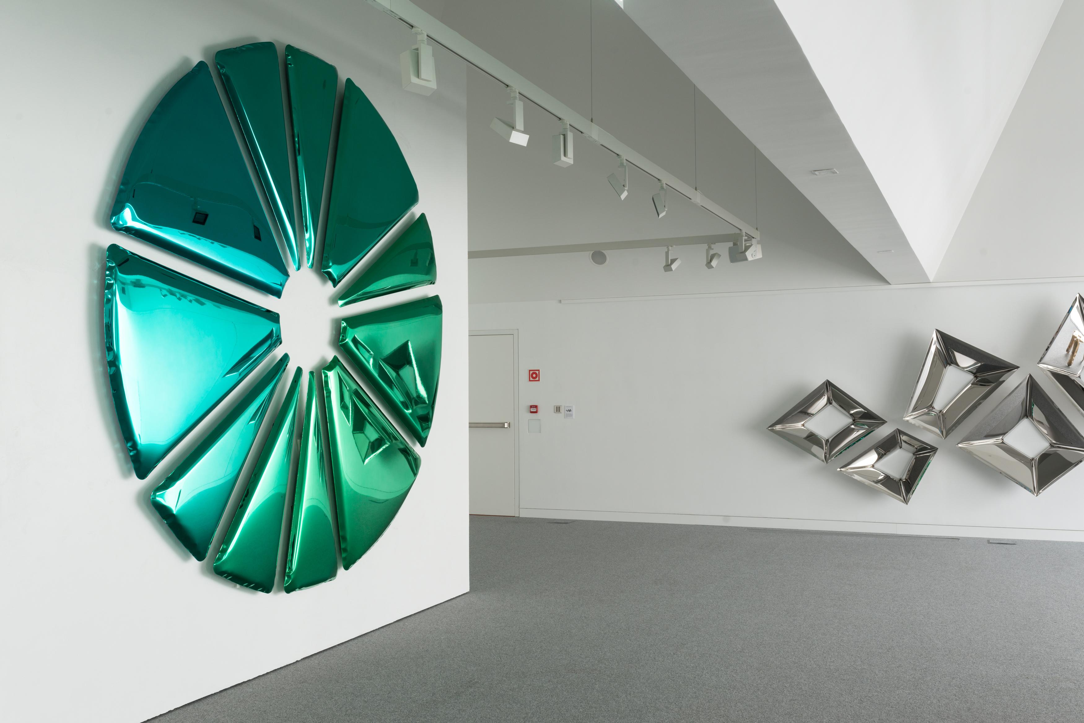 Die neueste Kreation von Oskar Zieta, der Multielement-Spiegel Nucleus, erinnert eher an eine Kunstinstallation als an einen Spiegel. Er besteht aus mehreren Elementen aus poliertem Edelstahl, die mit einer Farbbeschichtung versehen sind,
die einen