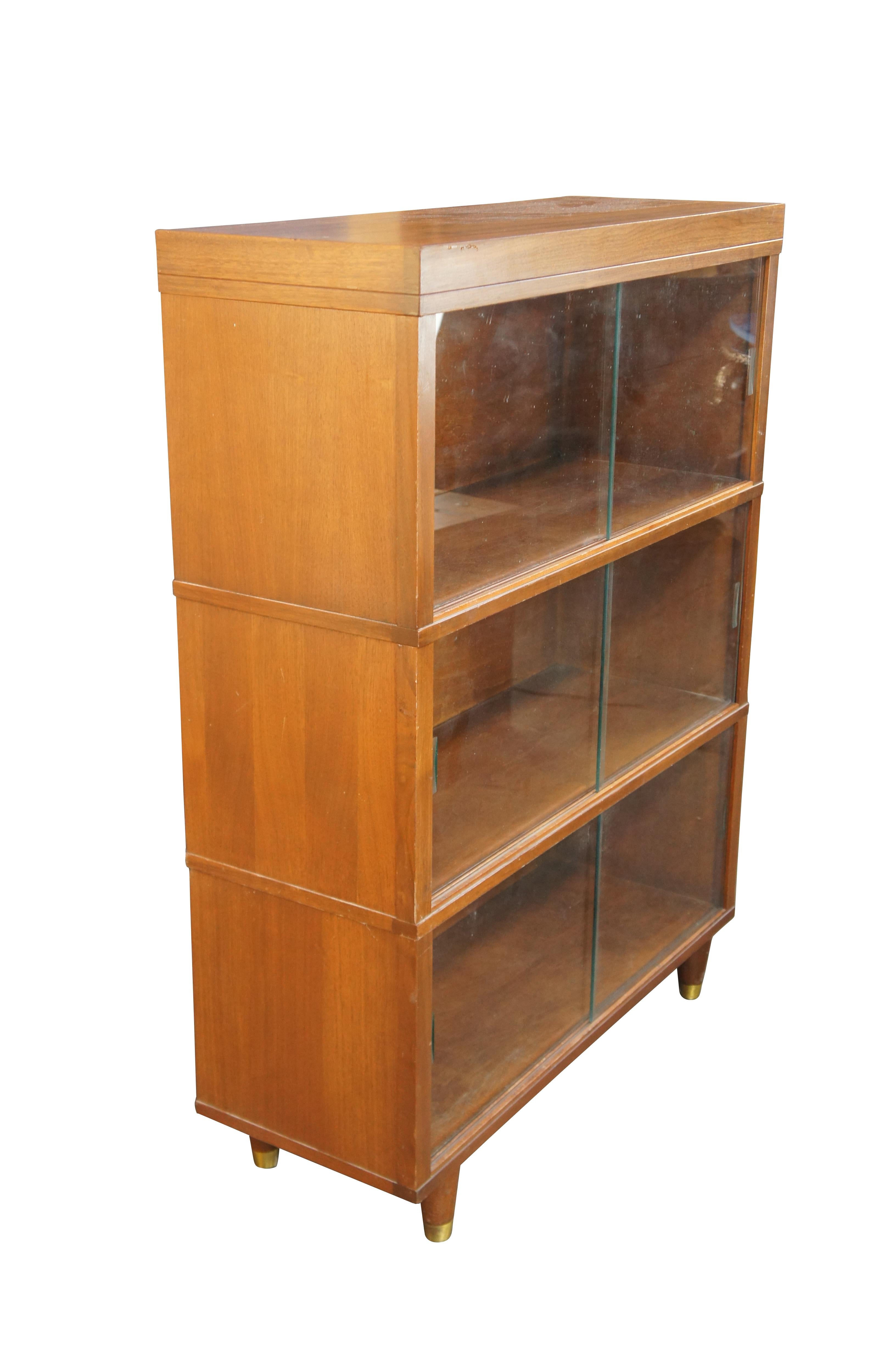 Mid Century Modern Barrister style display cabinet by Nucraft out of Grand Rapids Michigan. Features a walnut construction with glass sliding drawers over round tapered brass capped legs 

Nucraft Furniture Company was founded in 1942 in Grand