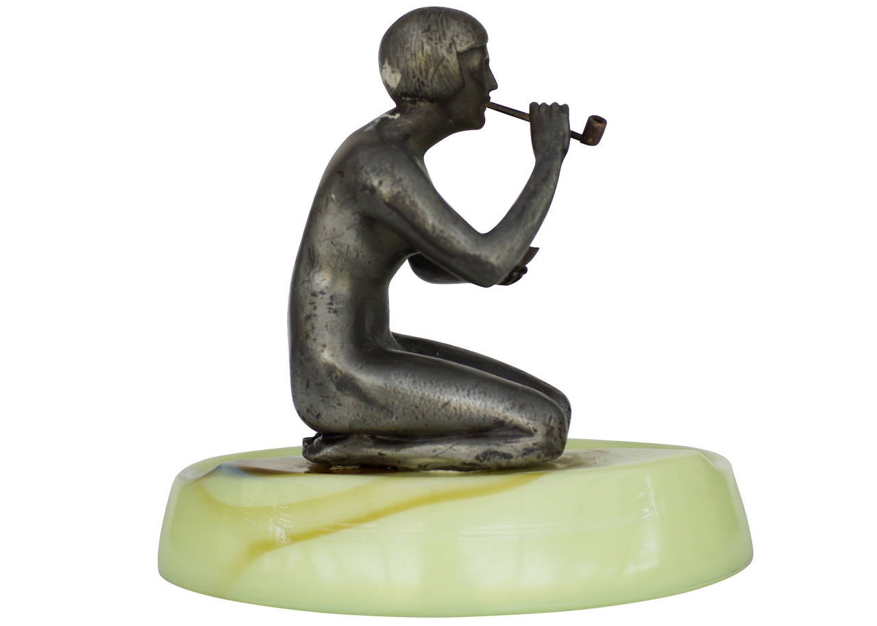 Made by Houzex, this brown and green slag ashtray features a spelter metal sculpture of a nude flapper girl smoking a long pipe. This is a great example of early Art Deco design and is reminiscent of the design and quality found in Frankart and