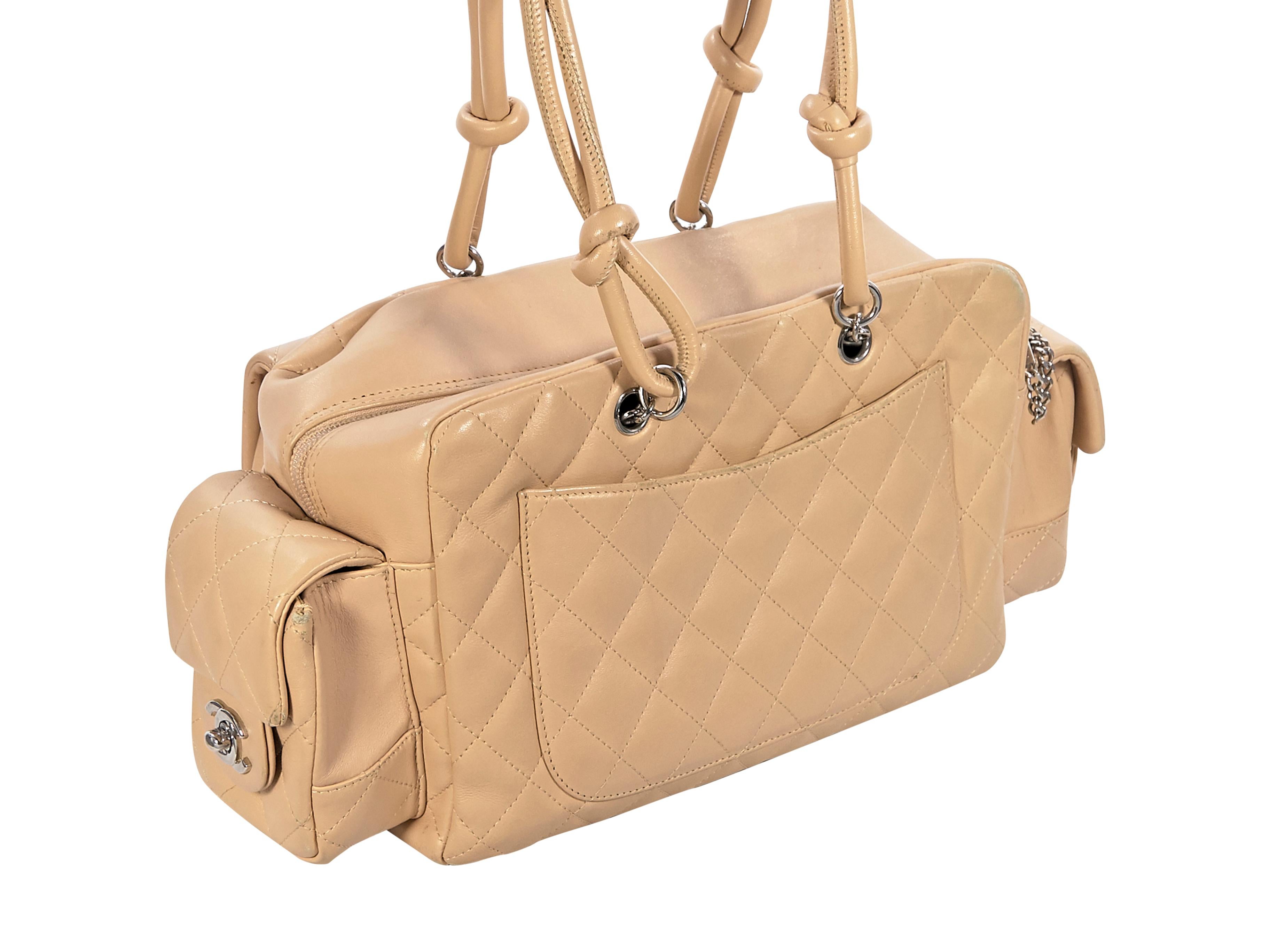 Product details:  Nude quilted leather Ligne Cambon Reporter shoulder bag by Chanel.  Dual shoulder straps.  Top zip closure.  Lined interior with inner zip pocket.  Exterior front and side twist-lock flap pockets.  Back exterior slide pocket. 