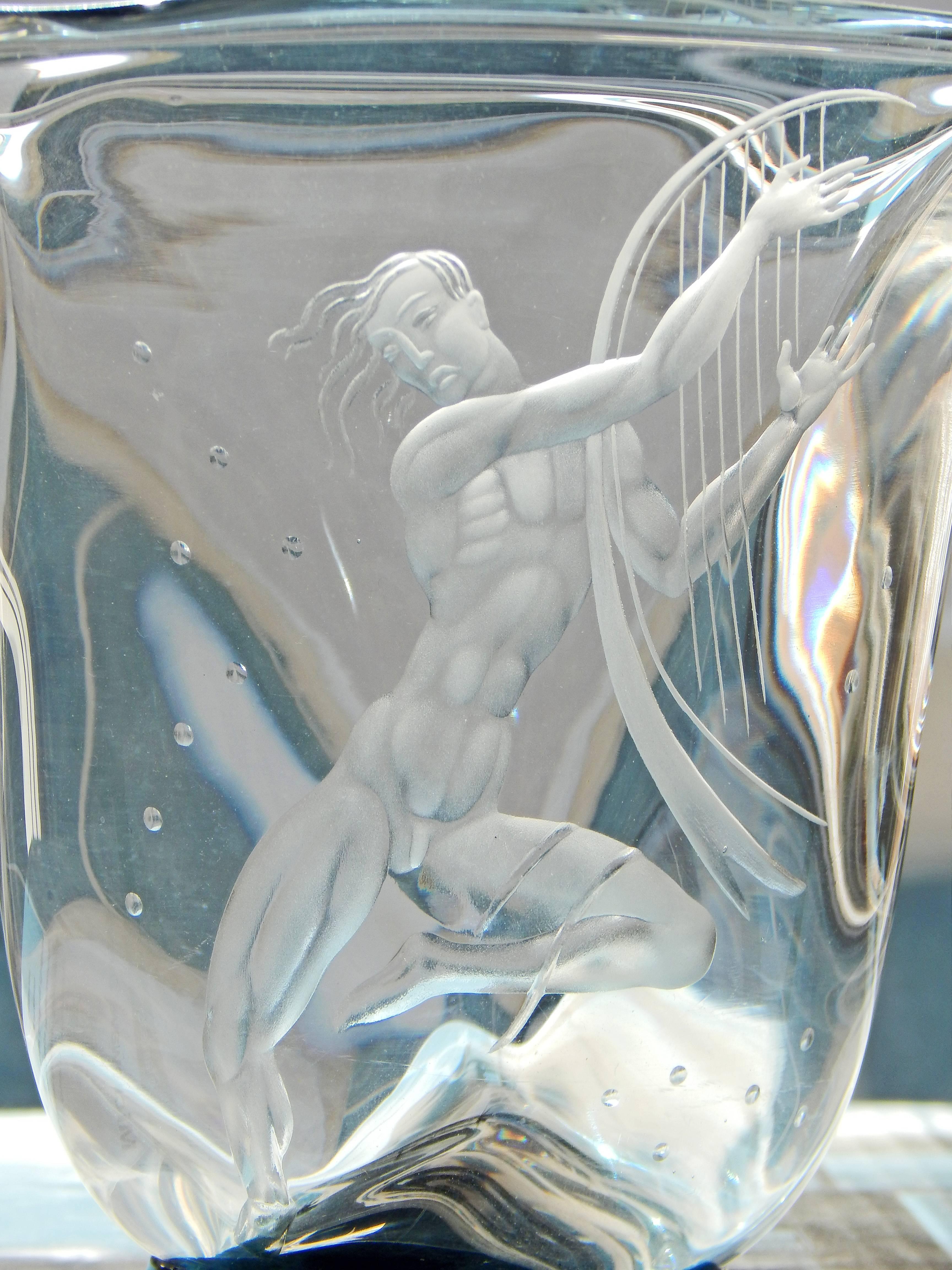 An especially rare example of Vicke Lindstrand's characterisitically elegant, stylized nude figures for the Orrefors glass company in Sweden, this piece features an engraved nude male figure playing a large harp. The figure, almost Mannerist in his