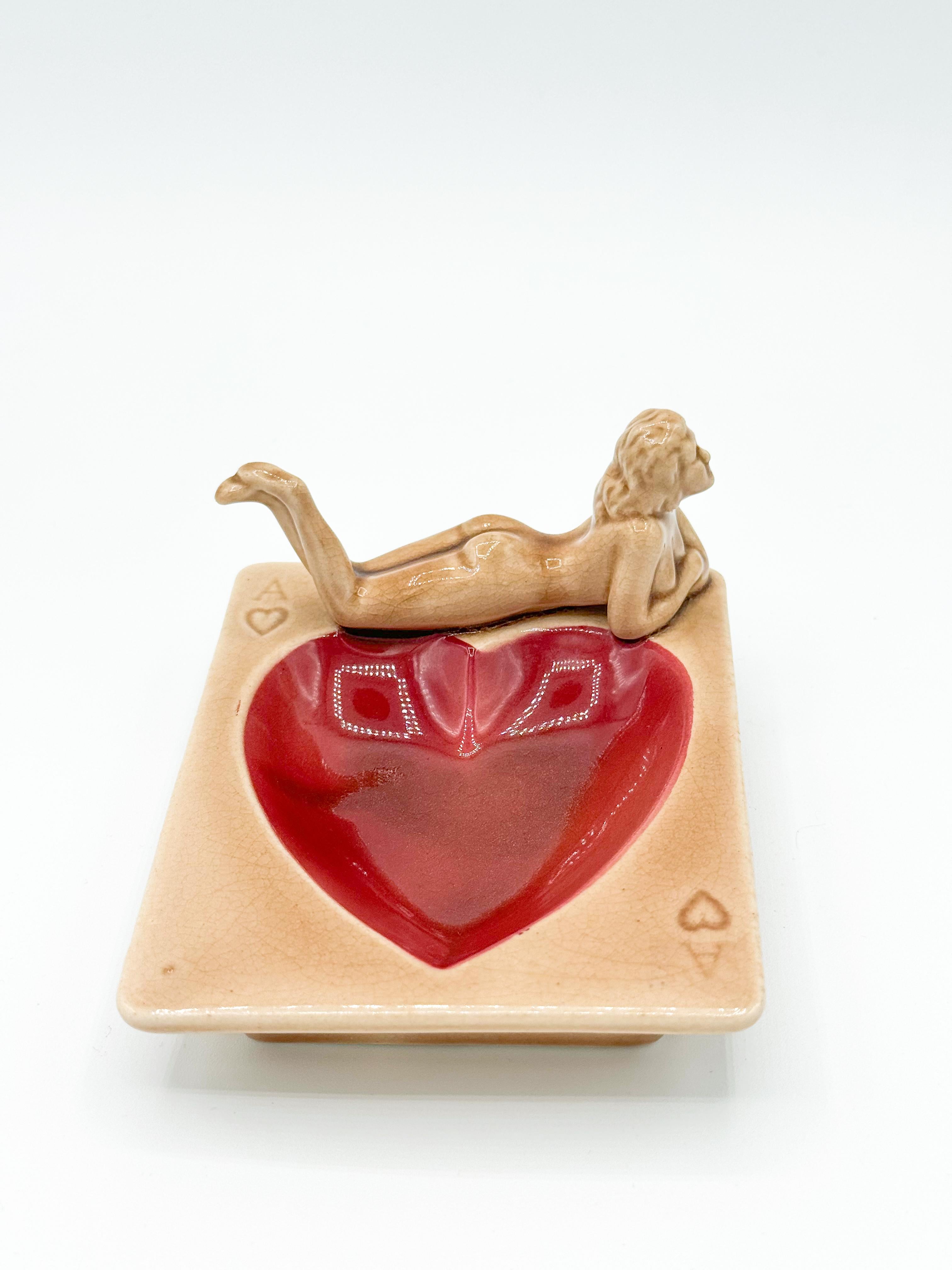 Vintage Heart Nude Ashtray made by Stafford in Japan during the 1940s. Featuring a charming pinup girl lounging gracefully, this porcelain piece captures the playful elegance of the era. Each ashtray is marked 