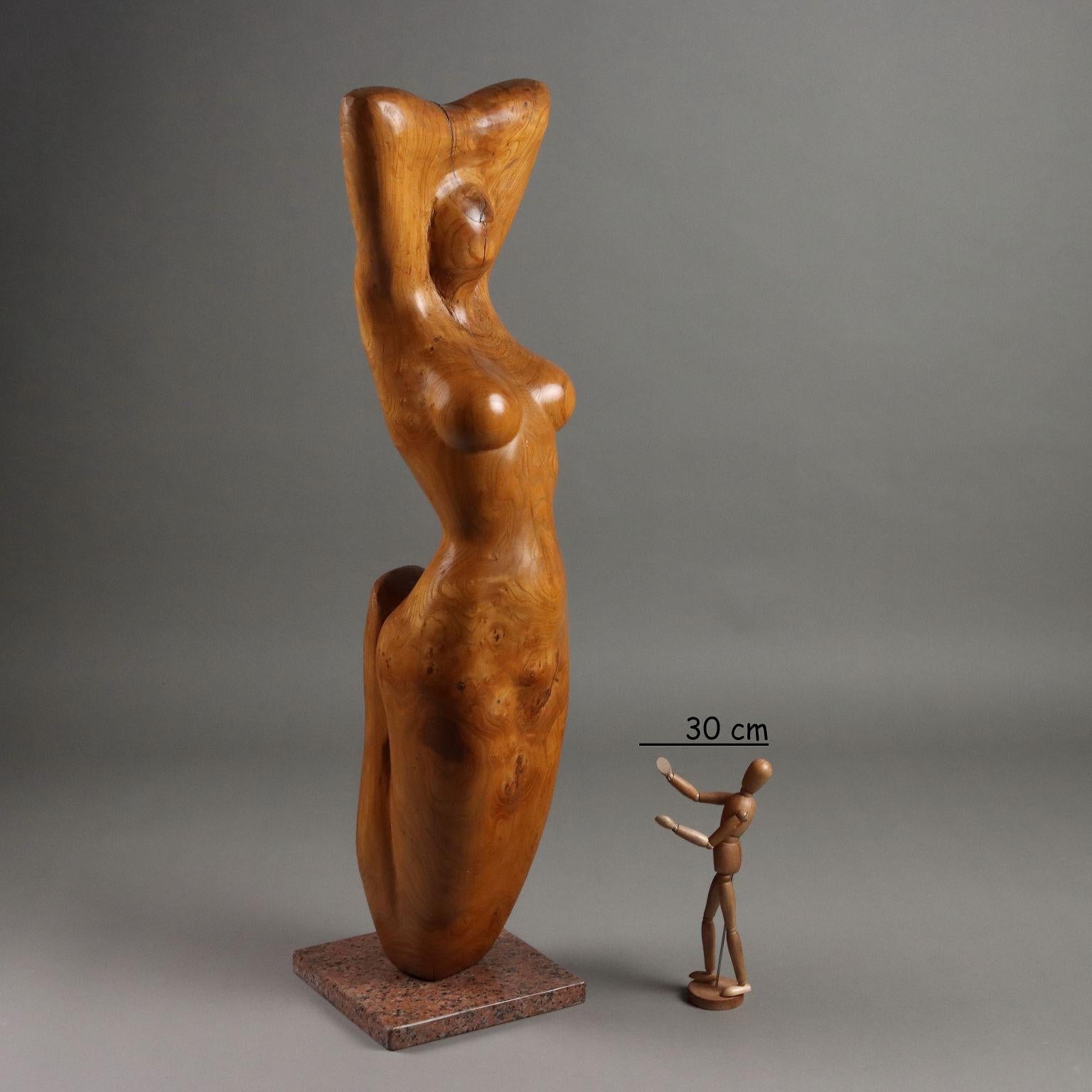 Carved wood sculpture on red granite base depicting female nude. Behind engraved signature of the author.