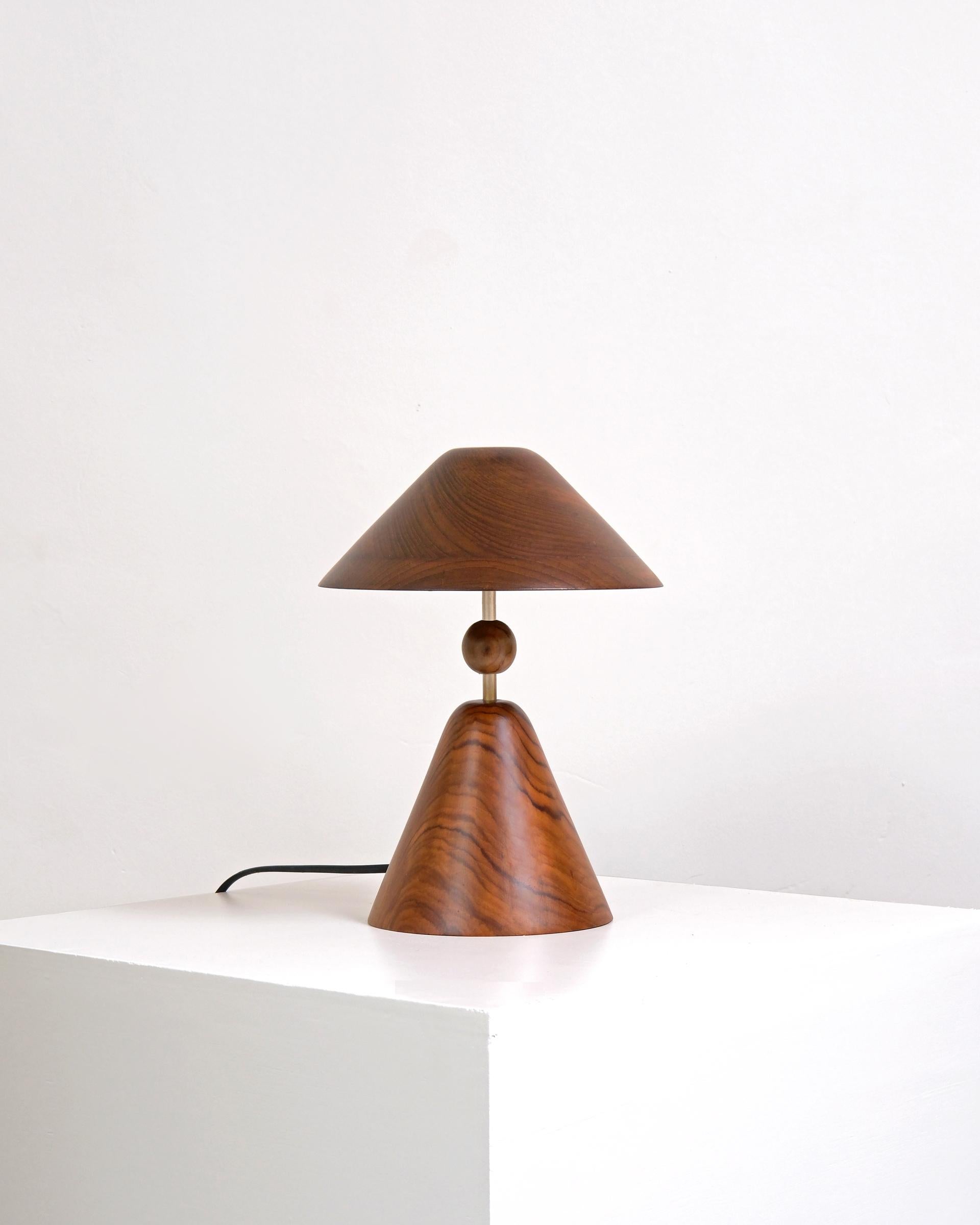 Nuit Table Lamp by Studio Indigene
Dimensions: D 20.32 x W 20.32 x H 27.94 cm
Materials: Reclaimed Teak Wood, Brass.
Colors Brown, Natural Wooden, Brass Finish.

Echoing the archetypical form of a table lamp, Nuit sits in corners with a soft glow -