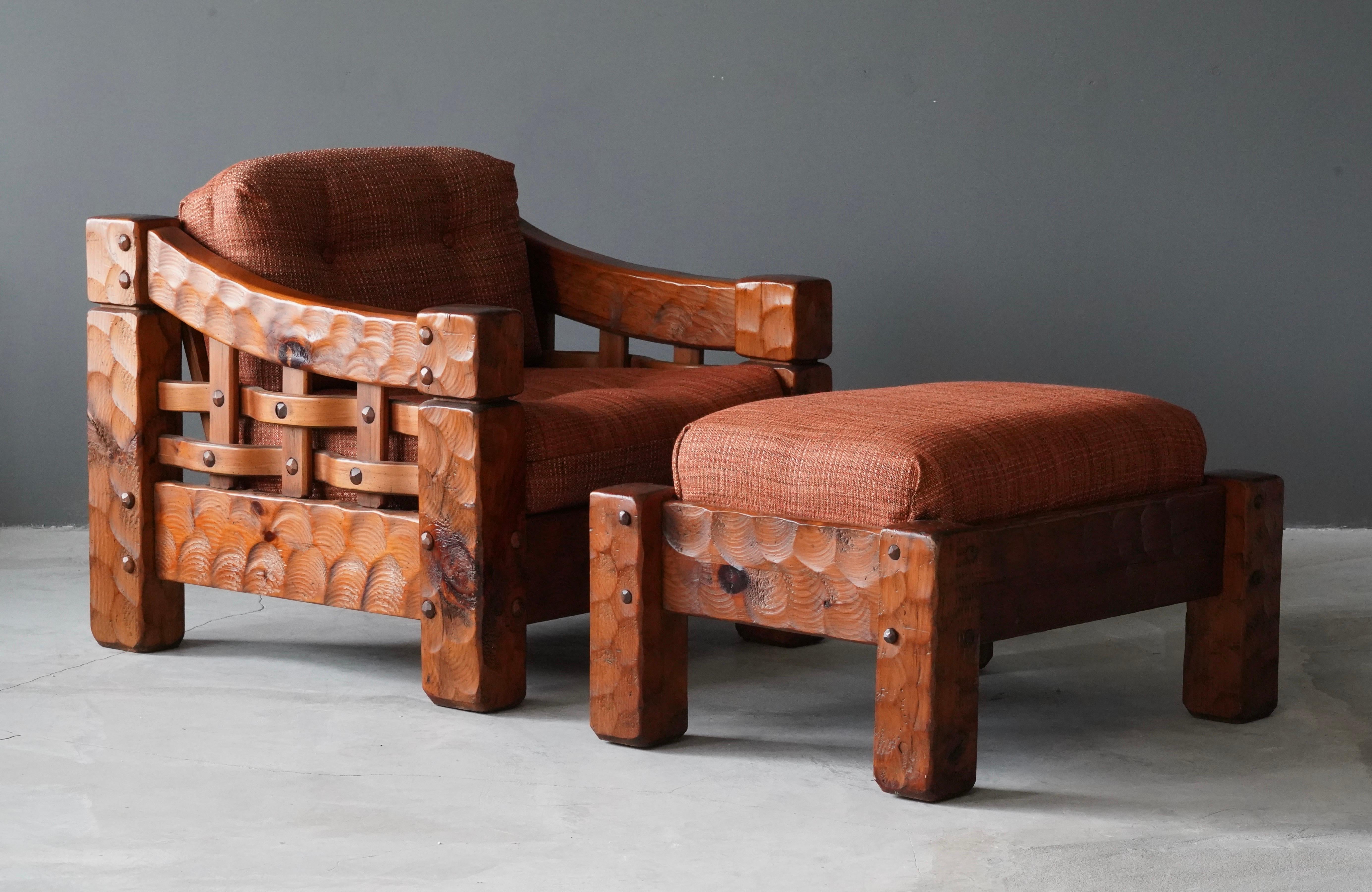 A pair of sizable lounge chairs with ottoman. In solid carved pine with revealed joinery. Features original red / orange fabric upholstered cushions. 

Large scale of chairs ottoman and material of cushions makes the chairs superbly comfortable.