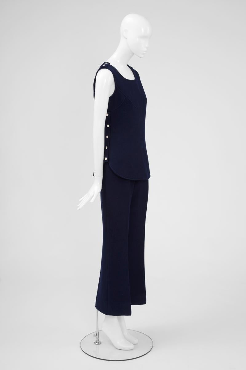 This ultra chic late 60’s - early 70’s haute couture Courrèges ensemble, is made up of a fitted tunic-top and high waisted trousers. Constructed in dark blue wool, this fully lined sleeveless tunic, labelled and numbered 10391, features a round
