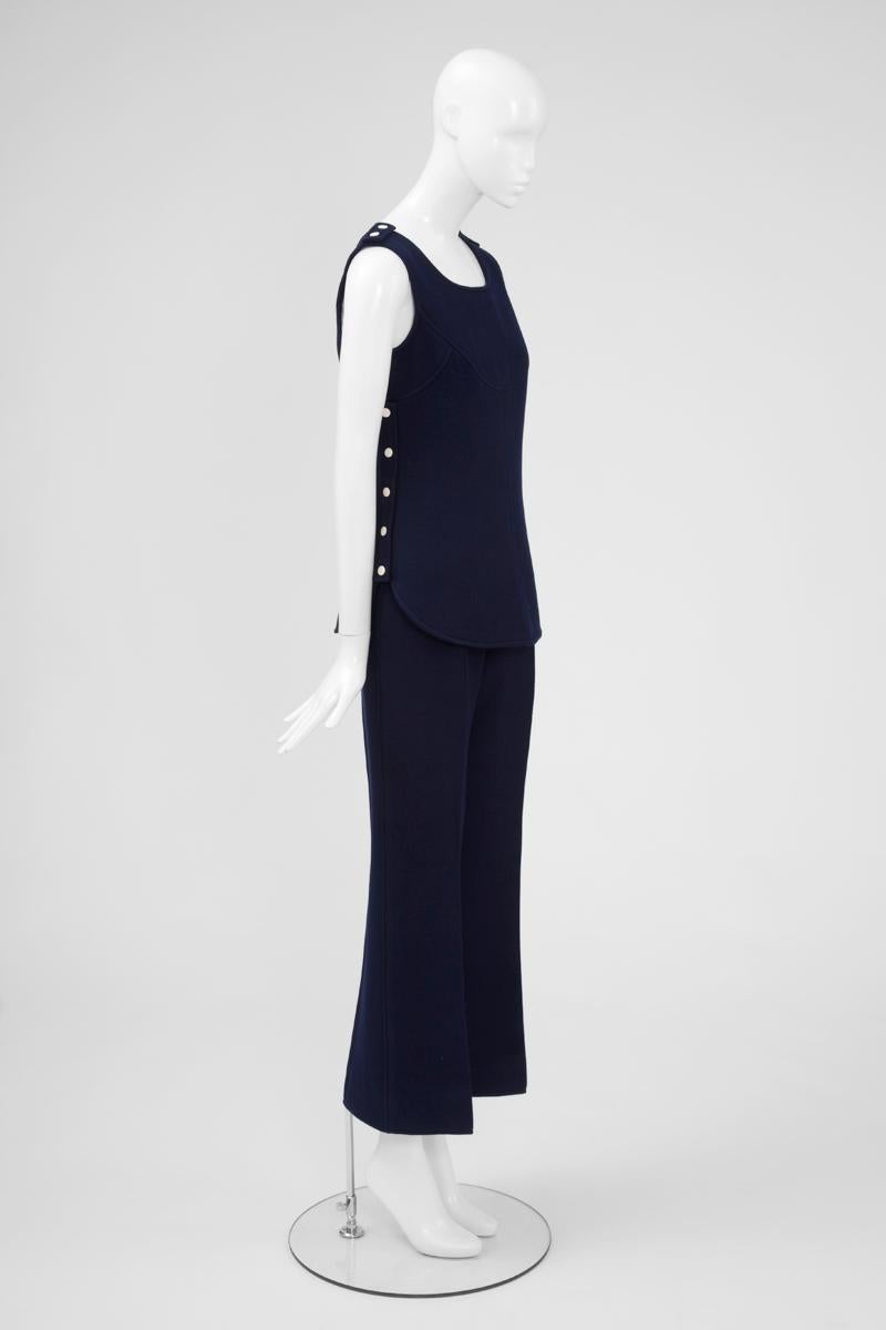 Este conjunto de alta costura Courrèges ultra chic de finales de los 60 y principios de los 70 se compone de una túnica ajustada y unos pantalones de talle alto. Confeccionada en lana azul oscuro, esta túnica sin mangas totalmente forrada,