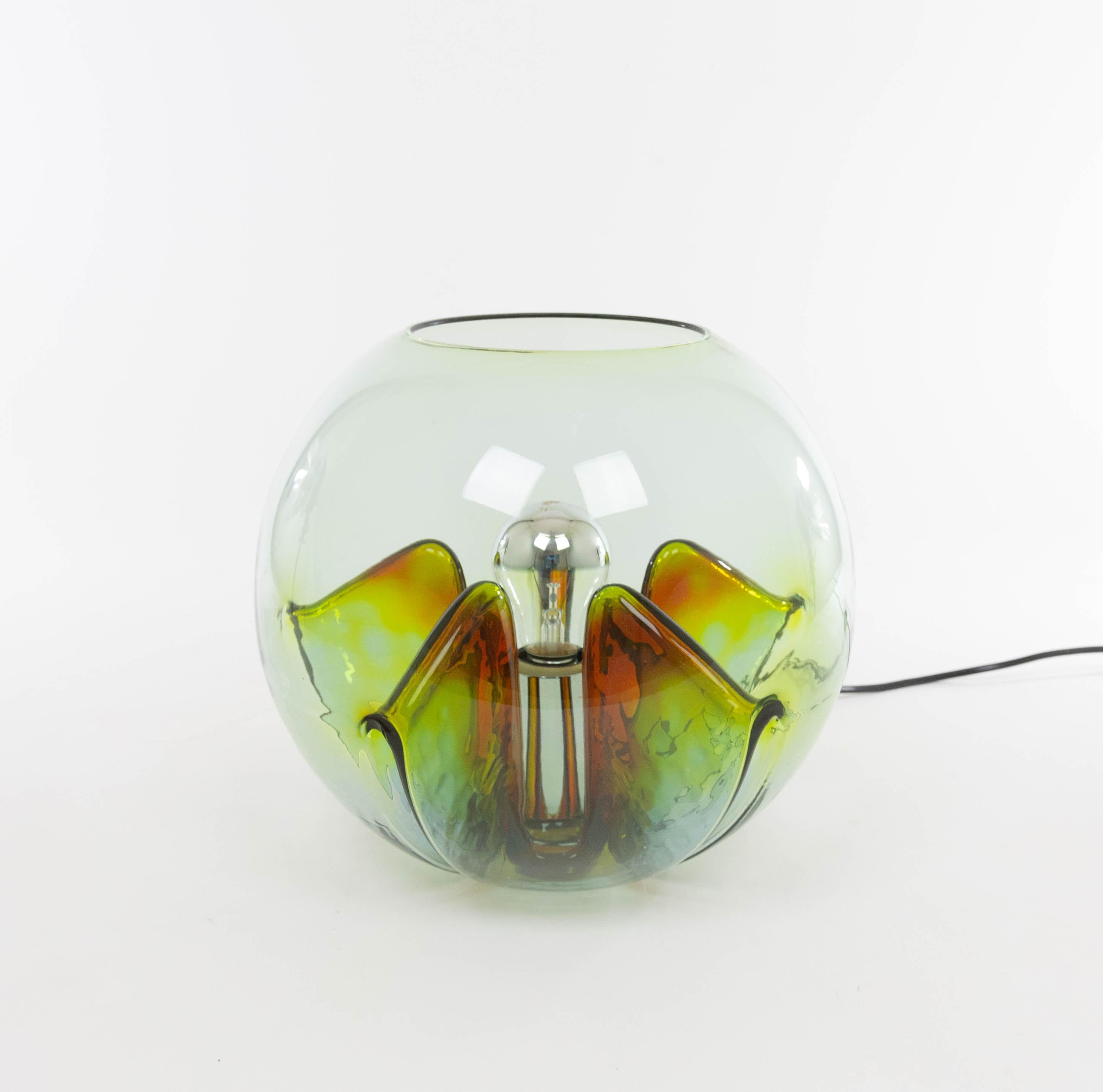 A Nuphar table lamp designed by Toni Zucchini and produced by VeArt, in the 1970s.

The lamp has a spherical glass body with five pleats folded inwards and a chromed metal fitting. The shades of yellow, green and maroon can be distinguished in