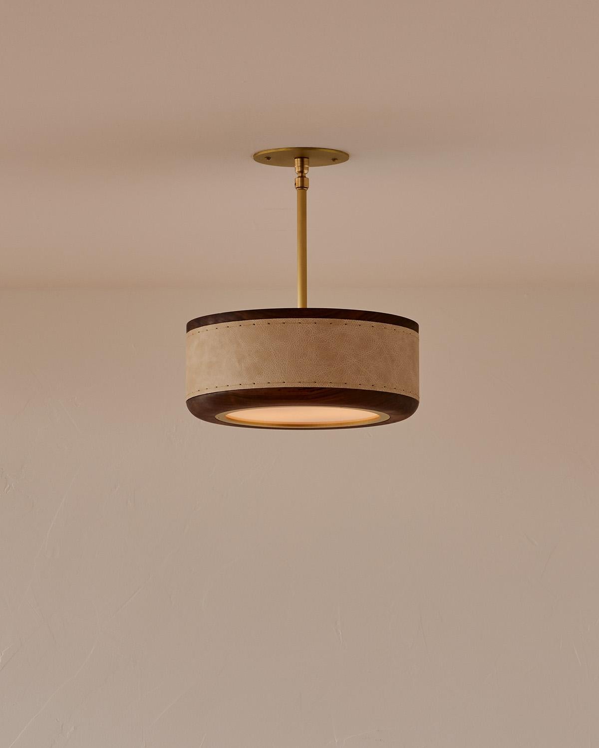 The Nura Ceiling Fixture combines hand-stitched leather over walnut accented by a brass pole and canopy. This fixture can either be hung as a ceiling surface mount or a pendant supported by a brass pole.

OVERALL DIMENSIONS
Shade: 12