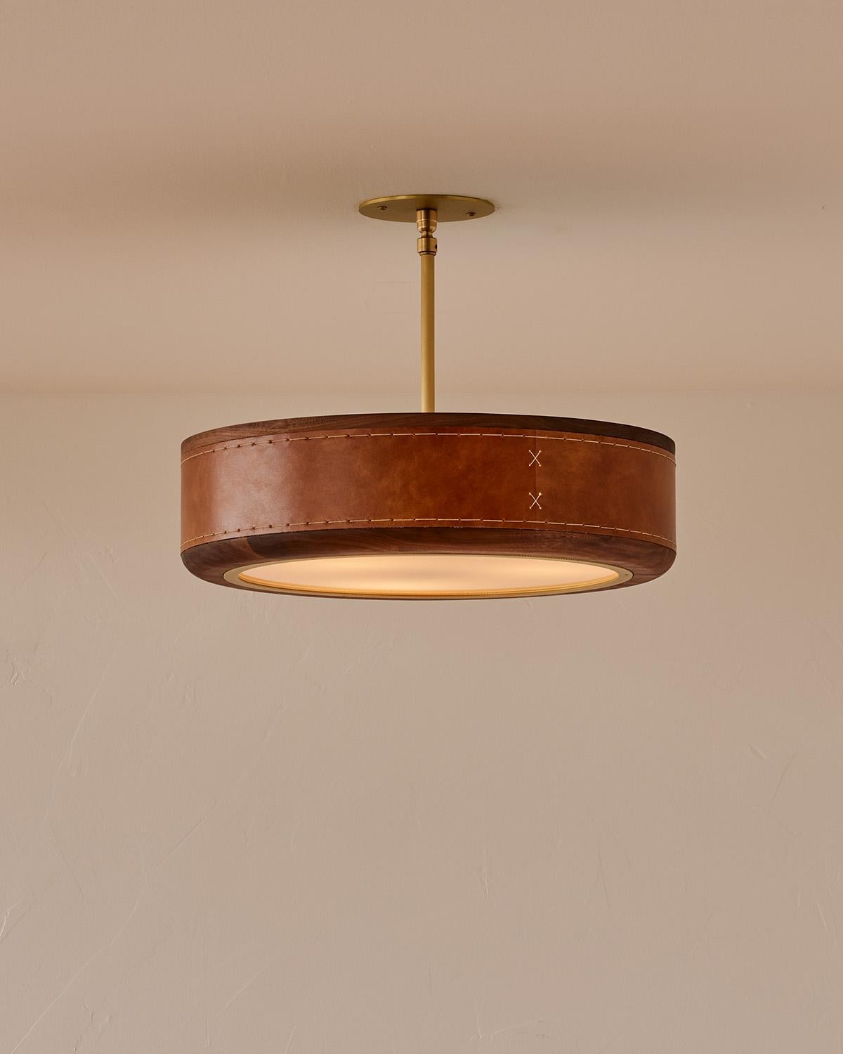 The Nura Ceiling Fixture combines hand-stitched leather over walnut accented by a brass pole and canopy. This fixture can either be hung as a ceiling surface mount or a pendant supported by a brass pole.

OVERALL DIMENSIONS
Shade: 18