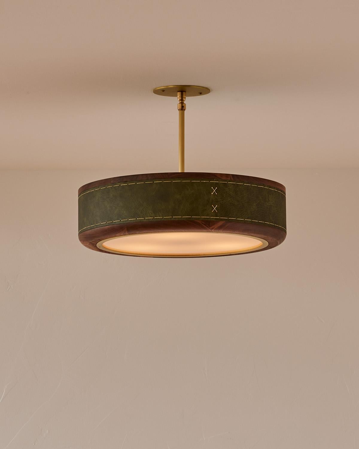 Le plafonnier Nura combine du cuir cousu à la main sur du noyer, accentué par un mât et un baldaquin en laiton. Ce luminaire peut être suspendu au plafond en tant que montage en surface ou en tant que suspension soutenue par un poteau en