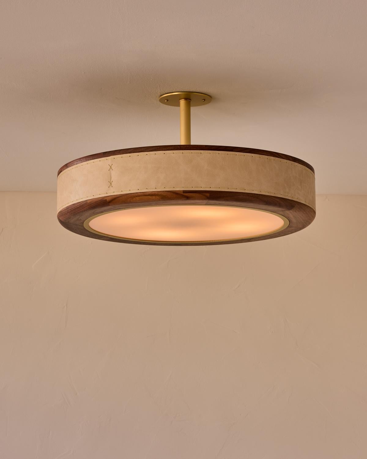 Le plafonnier Nura combine du cuir cousu à la main sur du noyer, accentué par un mât et un baldaquin en laiton. Ce luminaire peut être suspendu au plafond en tant que montage en surface ou en tant que suspension soutenue par un poteau en
