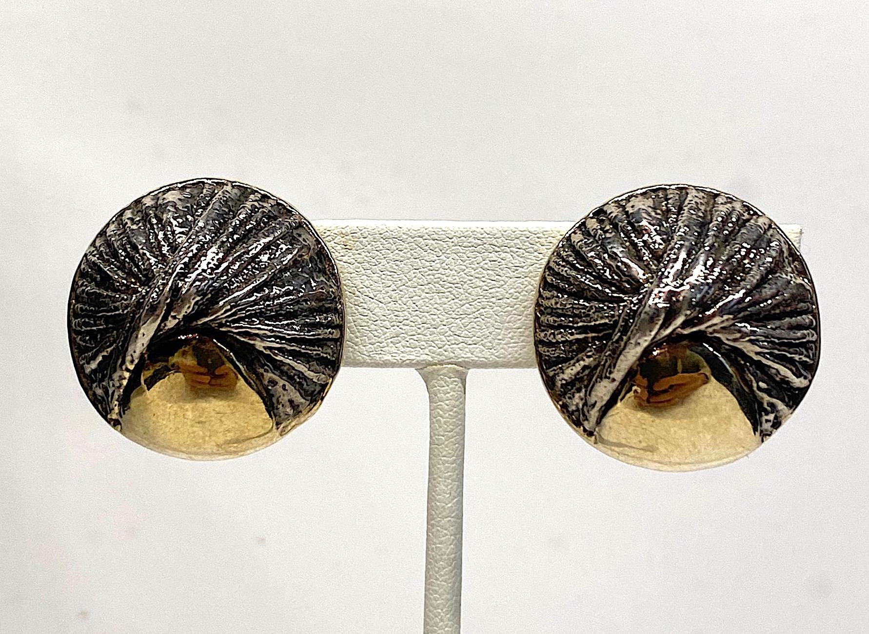 
Hand made pair of abstract modernist earrings in sterling silver with gold plate. The dome button style earrings have a sculptural quality with a patinated sterling twist design . Next to the twist is a gold plate area which nicely compliments the