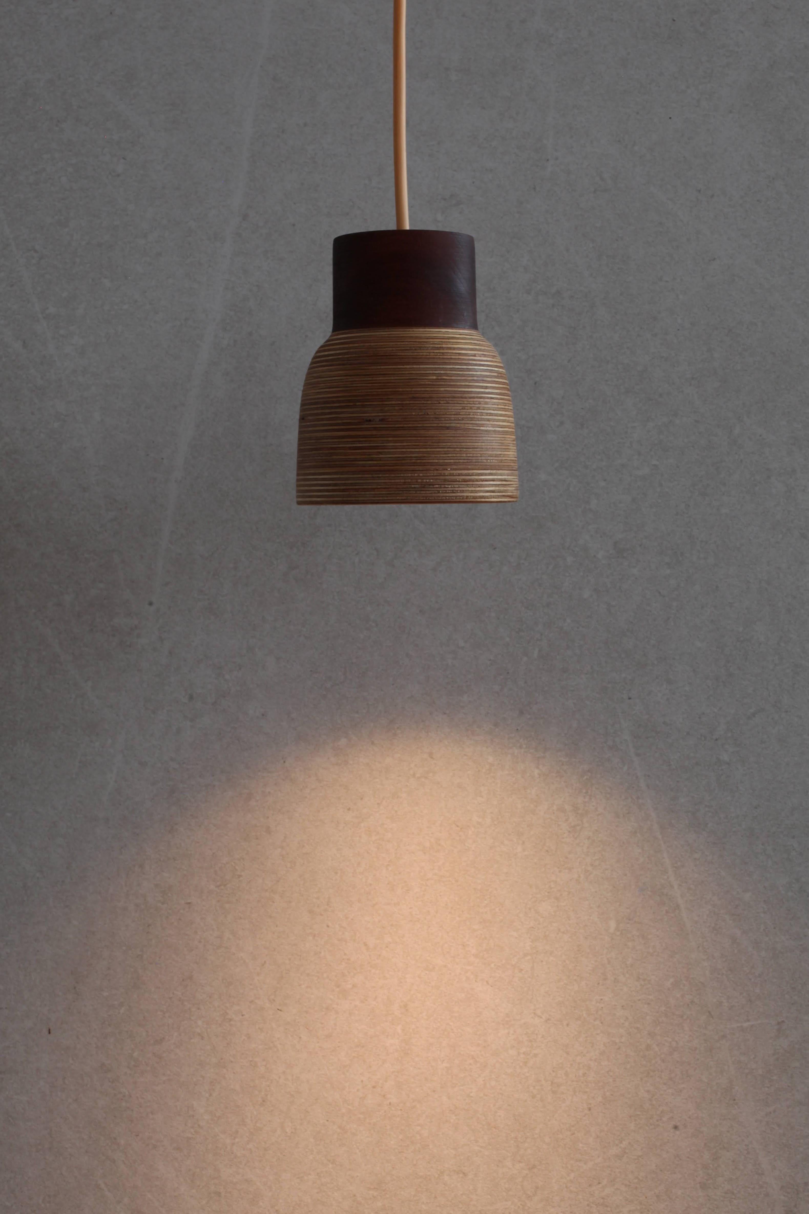 The Nutshell pendant, similar to the Nut Husk, is made from colourful layers of sustainable Baltic Birch ply with a cylinder of richly dark brown sapele wood on top. The pendant is available in plain wood or with a geometric style section of white.