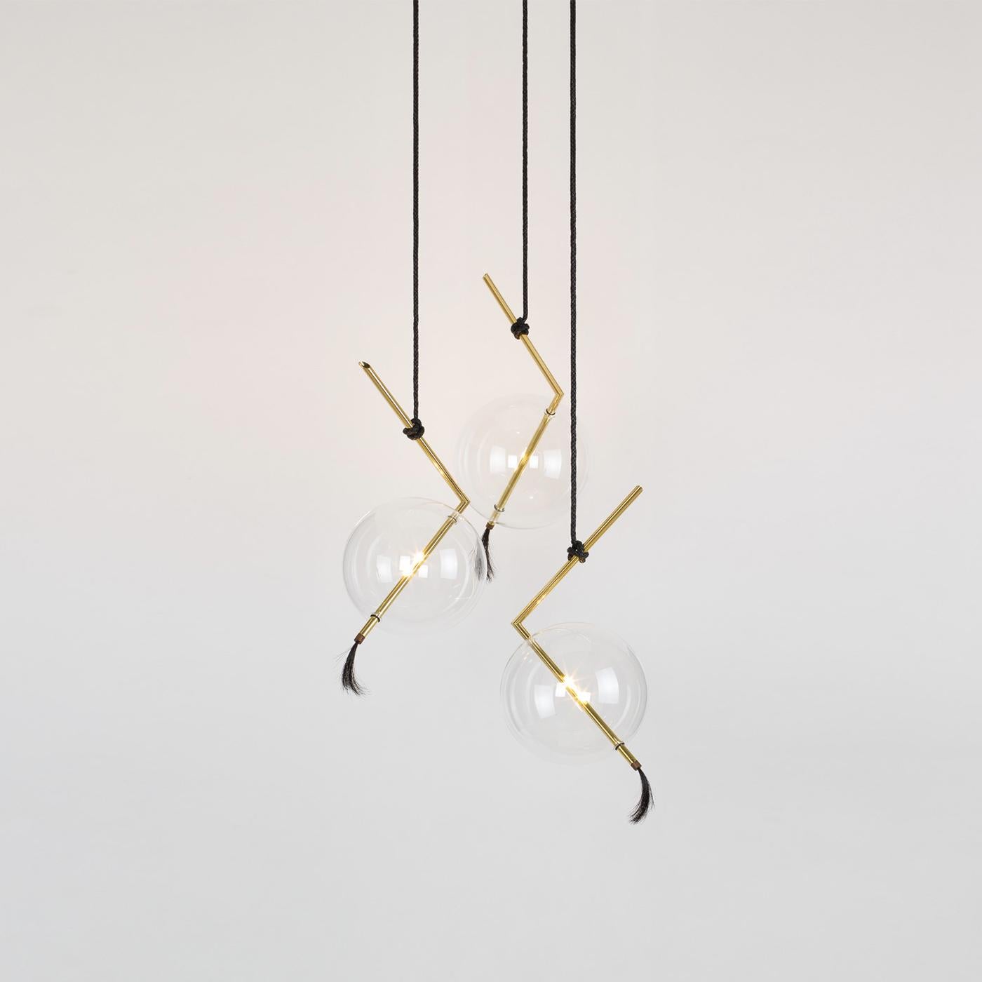 This contemporary chandelier is inspired by a circus trapeze and its form allows for the lights to be adjusted separately in any direction. The glass elements are hand blown in different forms linked by brass bars and hung on linen cords from hub