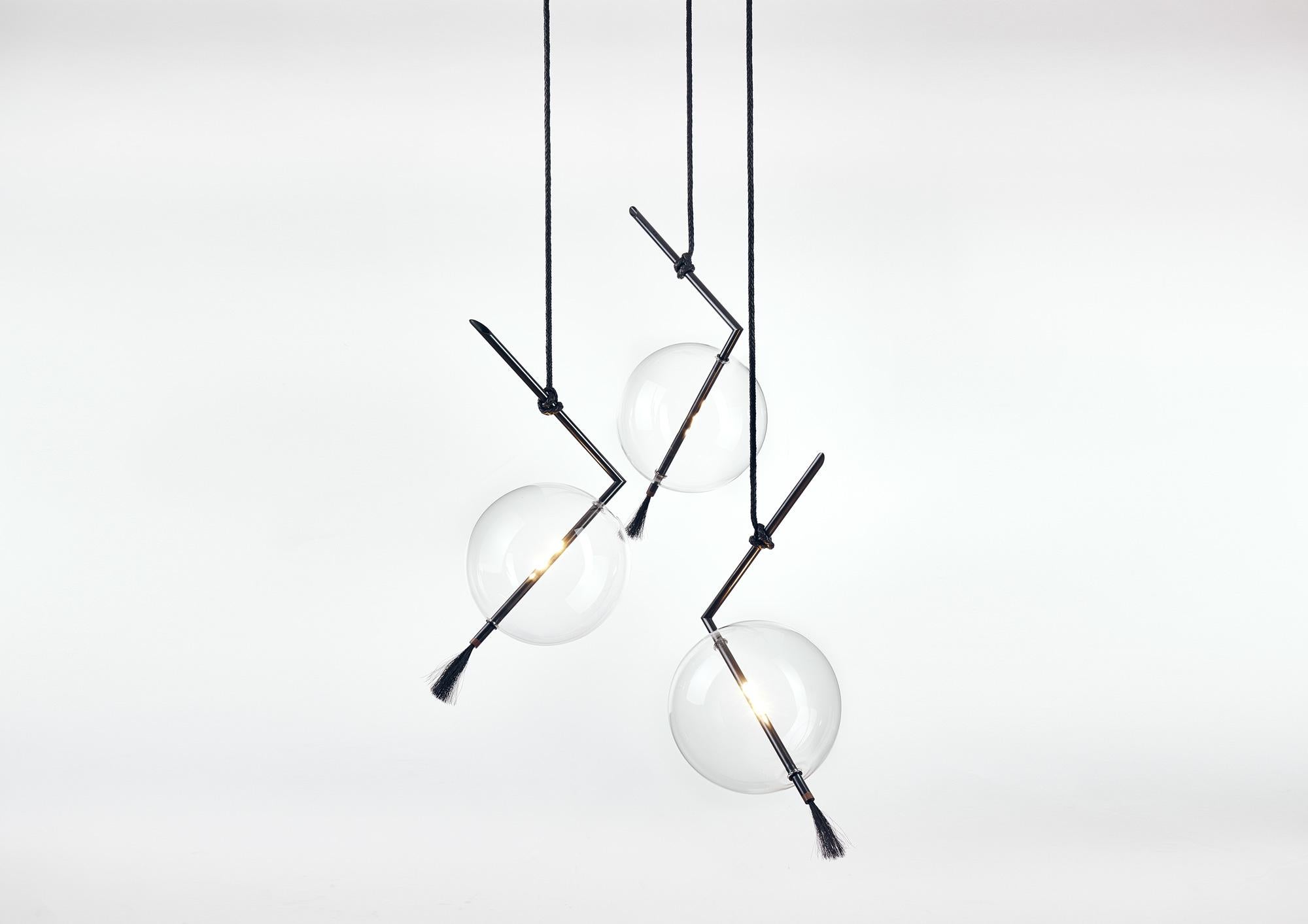 Nuvola black three lights customizable chandelier/pendant contemporary light-fixture floats in space like a jewel hanging from the ceiling.
The pure geometry of the blackened brass rod containing the led light contrasts with the ephemeral