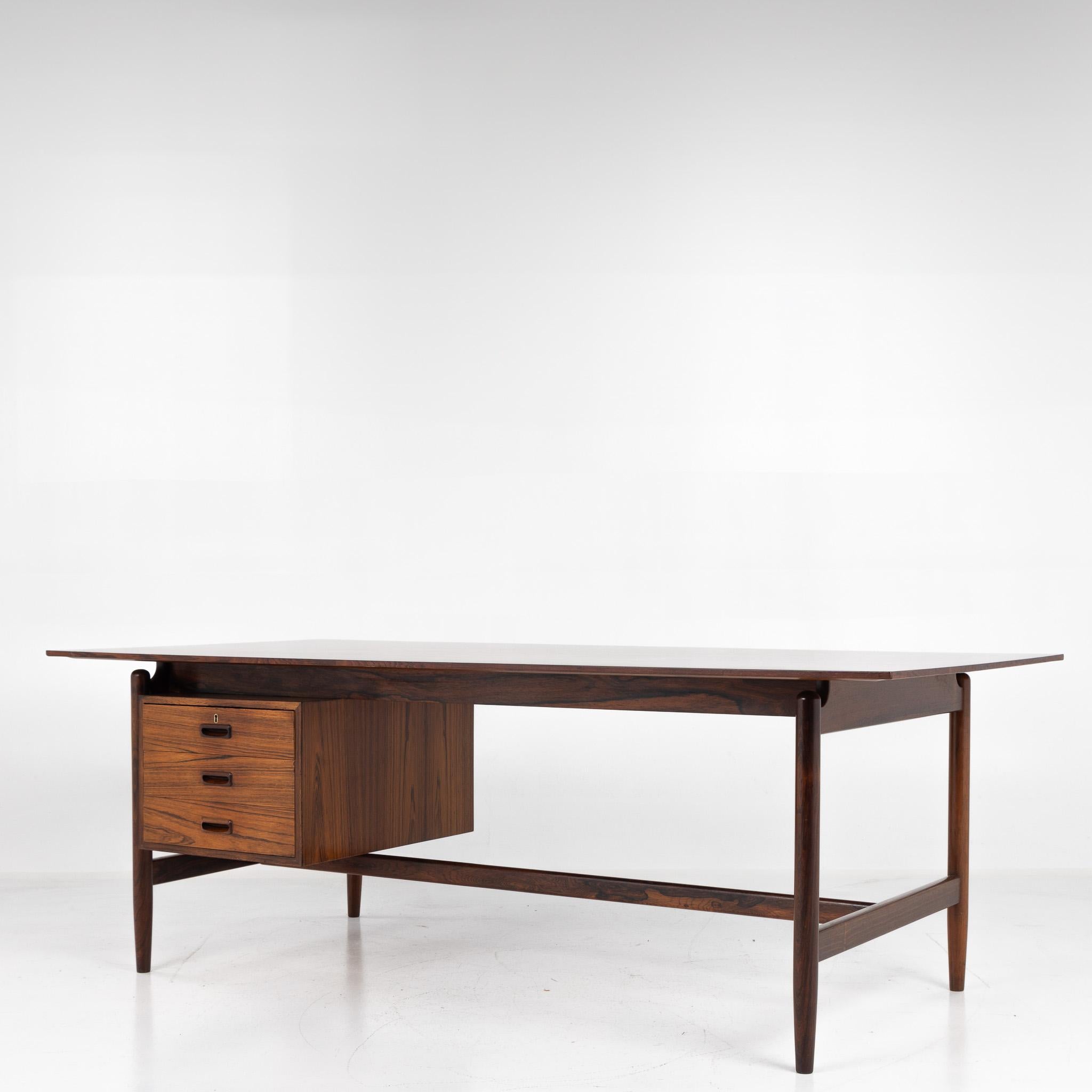 NV 50 - Desk in rosewood on round, tapered legs. Front with drawer module with three drawers. Designed in 1945. Architect Finn Juhl for master cabinetmaker Niels Vodder.