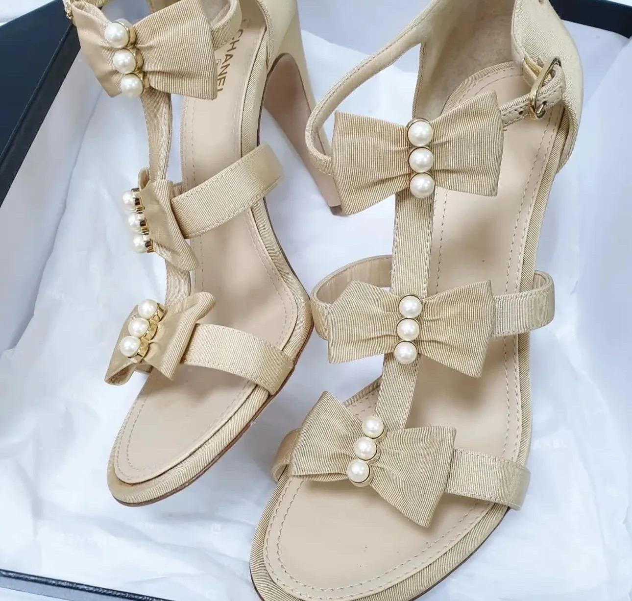 Gehen Sie stilvoll aus mit diesen umwerfenden Chanel Riemchensandalen aus cremefarbenem Leder! Diese eleganten Absätze verfügen über charmante Schleifen auf der Vorderseite, die mit Kunstperlen verziert sind und jedem Outfit einen Hauch von