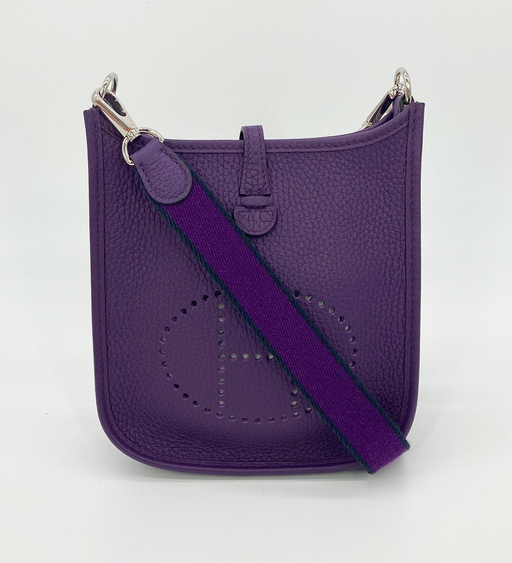 NWOT Hermes Purple Clemence Evelyne 16 TPM in new unused condition. Purple clemence leather exterior trimmed with silver palladium hardware and two tone woven canvas shoulder strap. Top snap strap closure opens to an unlined interior with enough