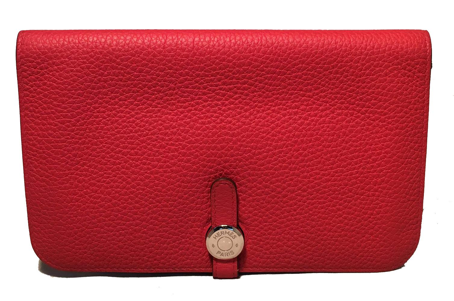 NWOT Hermes Red Togo Dogon Duo Wallet in like new condition. Red togo leather exterior trimmed with silver palladium hardware. Signature slip strap closure opens to a matching red lambskin lined interior that holds 5 interior pockets and a removable