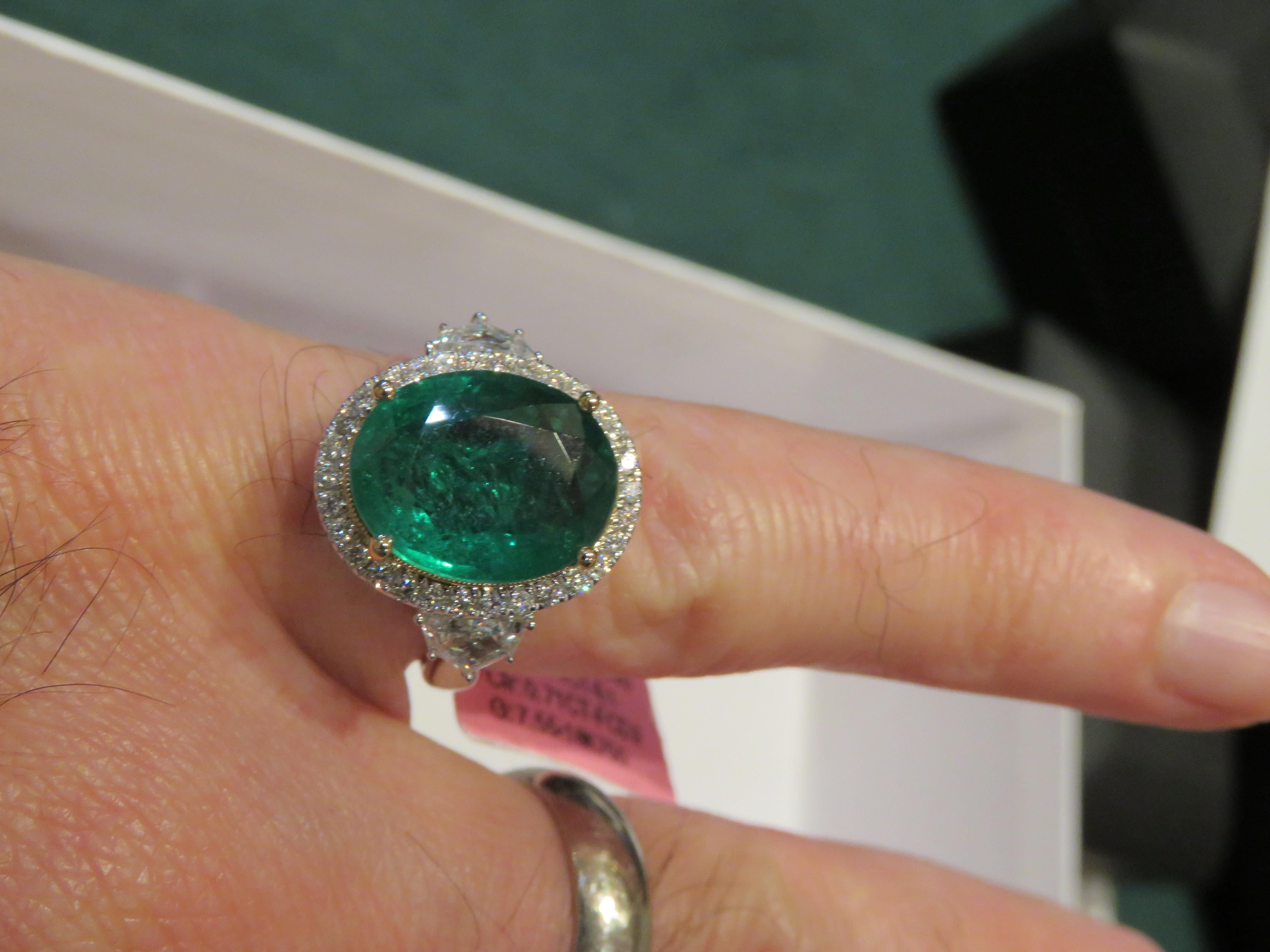 The Following Item we are offering is a Rare Important Radiant 18KT Gold Large Fancy Glittering Large Emerald surrounded with a Halo of Diamonds and Diamond Baguettes on side.  Ring is comprised of A LARGE Gorgeous Fancy Emerald sitting atop and
