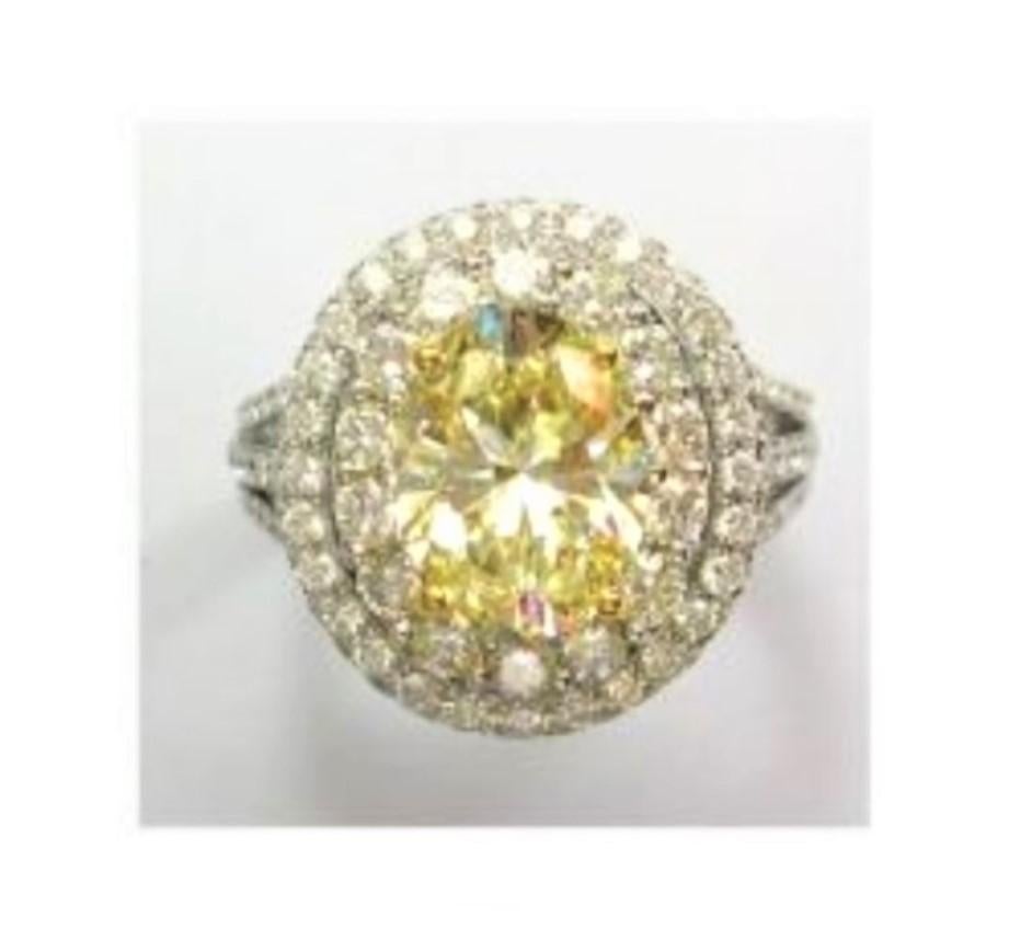 The Following Items we are offering is a Rare Important Radiant 18KT White Gold Elaborate Fancy Yellow Diamond White Diamond Ring. This Magnificent Ring features a Rare Large Sparkling Fancy Oval Cut Yellow Diamond surrounded with a Double Halo of