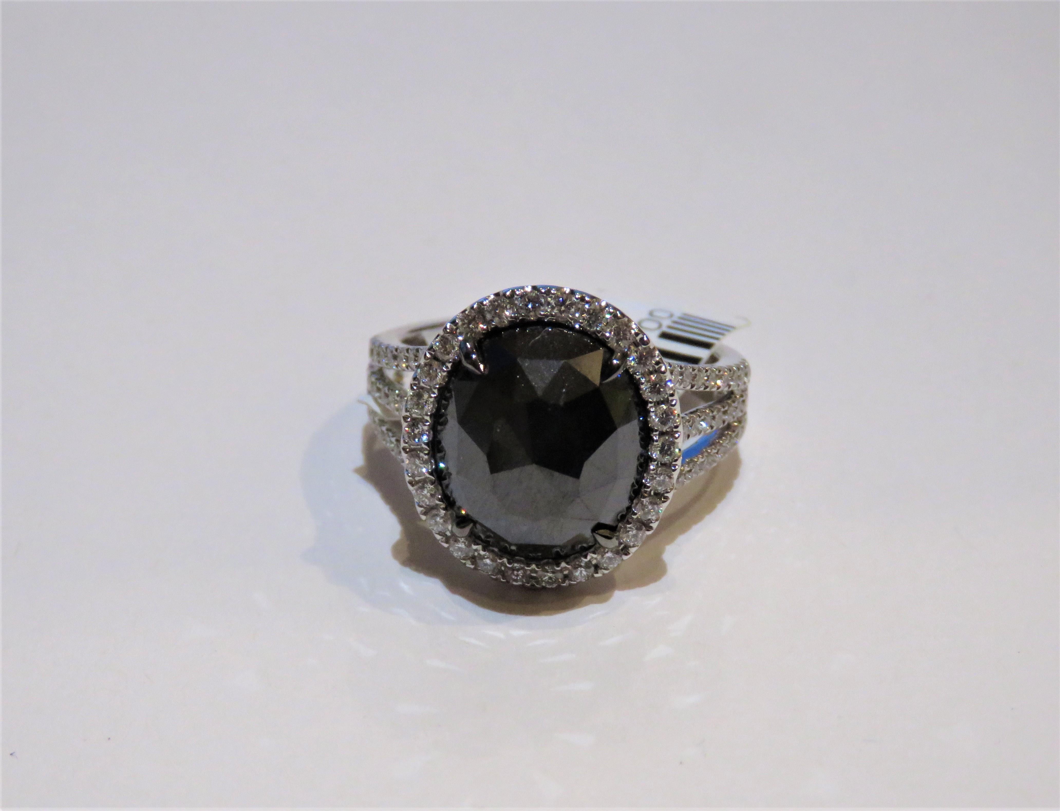 The Following Item we are offering is this Extremely Rare Beautiful 18KT Gold Fine Rare Large Fancy Black Diamond Ring. This Magnificent Ring is comprised of Rare Fine Large Faceted Oval Black Diamond surrounded with a Halo of Diamonds and 3 rows of