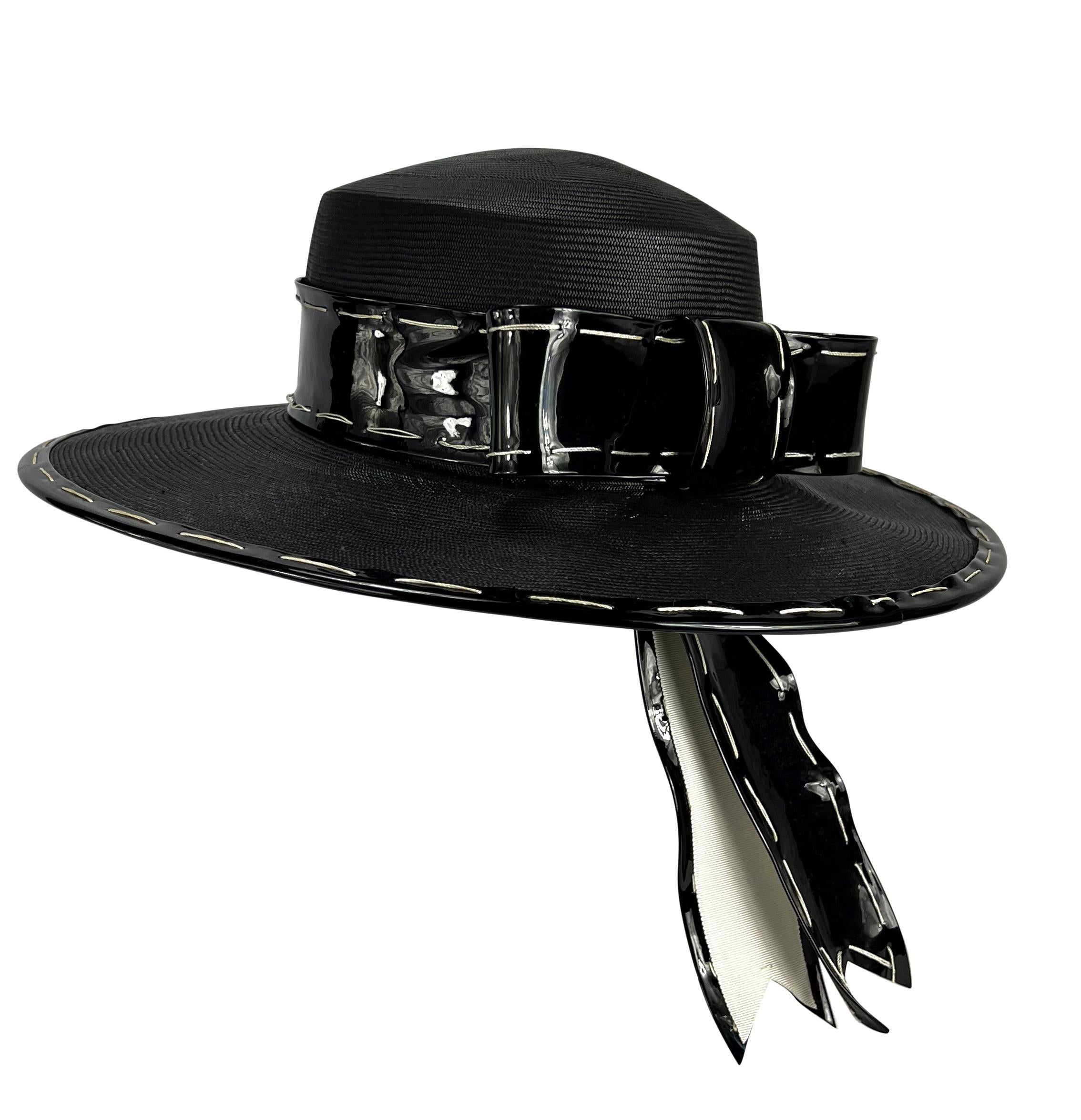 Presenting a fabulous black straw Yves Saint Laurent chupalla-style hat. From the 1970s, this hat is constructed entirely of black straw and features a shiny black bow around the base of the hat. The bow playfully pokes through the hat with the