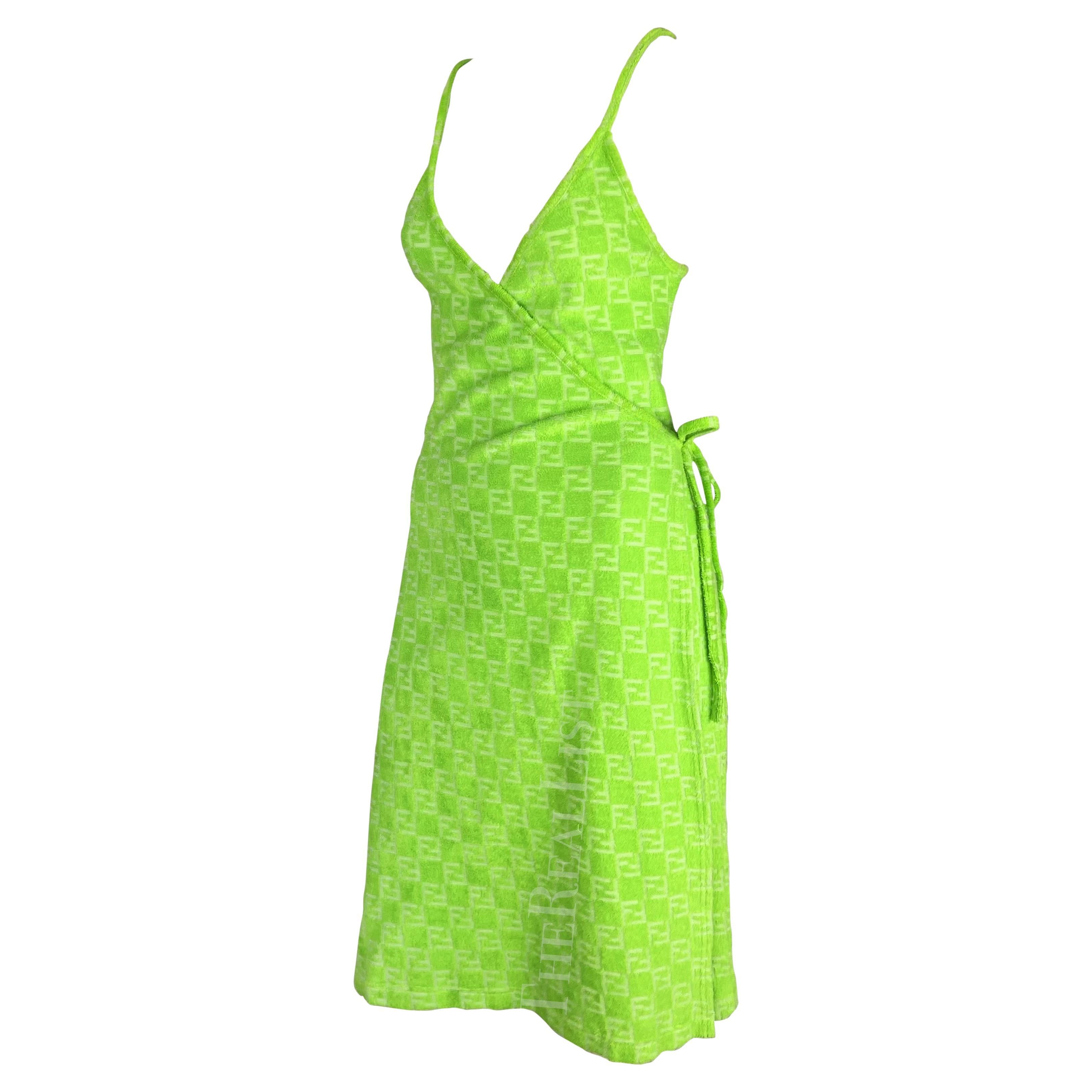 Présentation d'une incroyable robe portefeuille Fendi vert fluo, dessinée par Karl Lagerfeld. Datant des années 1990, cette robe portefeuille est entièrement réalisée en tissu éponge et porte le monogramme Fendi 'FF' en relief. Simple et chic, cette