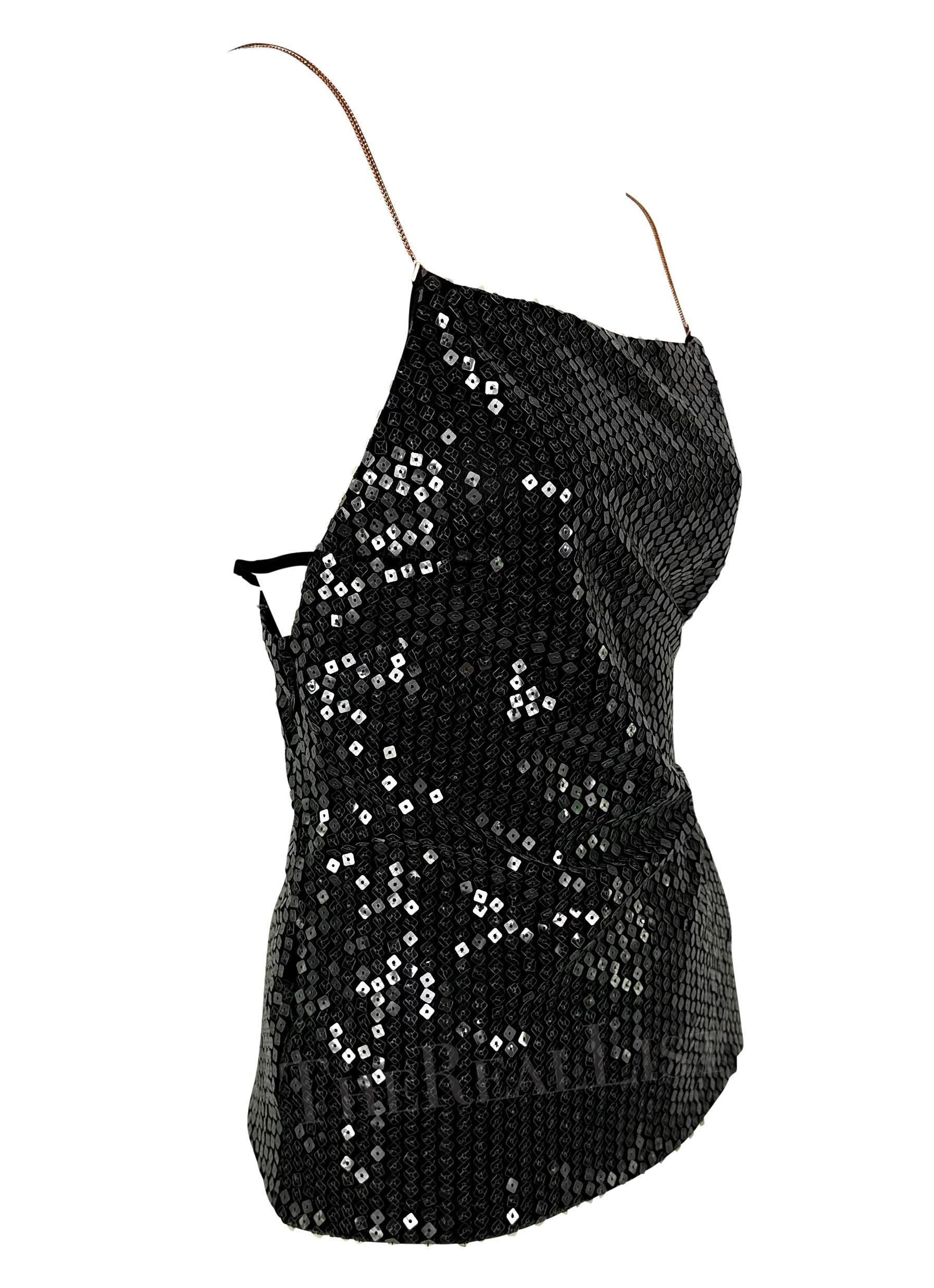 Presentamos una fabulosa camiseta de tirantes Gianni Versace de pedrería negra, diseñada por Donatella Versace. Desde 1999, este top está cubierto de lentejuelas transparentes que captan perfectamente la luz con cada movimiento. El top presenta un