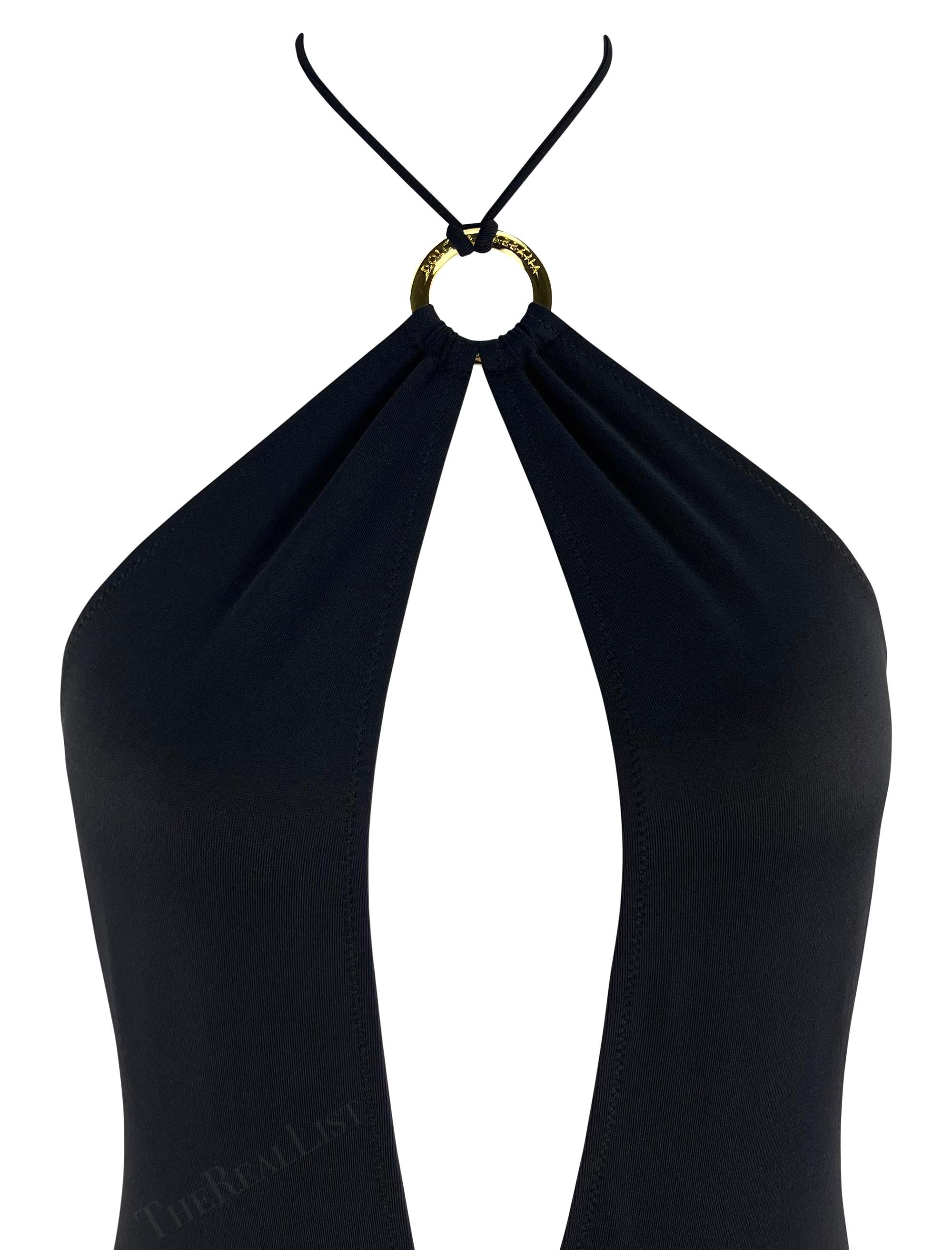 From the early 2000s, this stunning black Dolce & Gabbana halterneck one-piece swimsuit prominently features a gold-tone metal ring above the bust. This branded metal accent connects to the halterneck tie. This ultra-sexy one-piece swimsuit/bodysuit