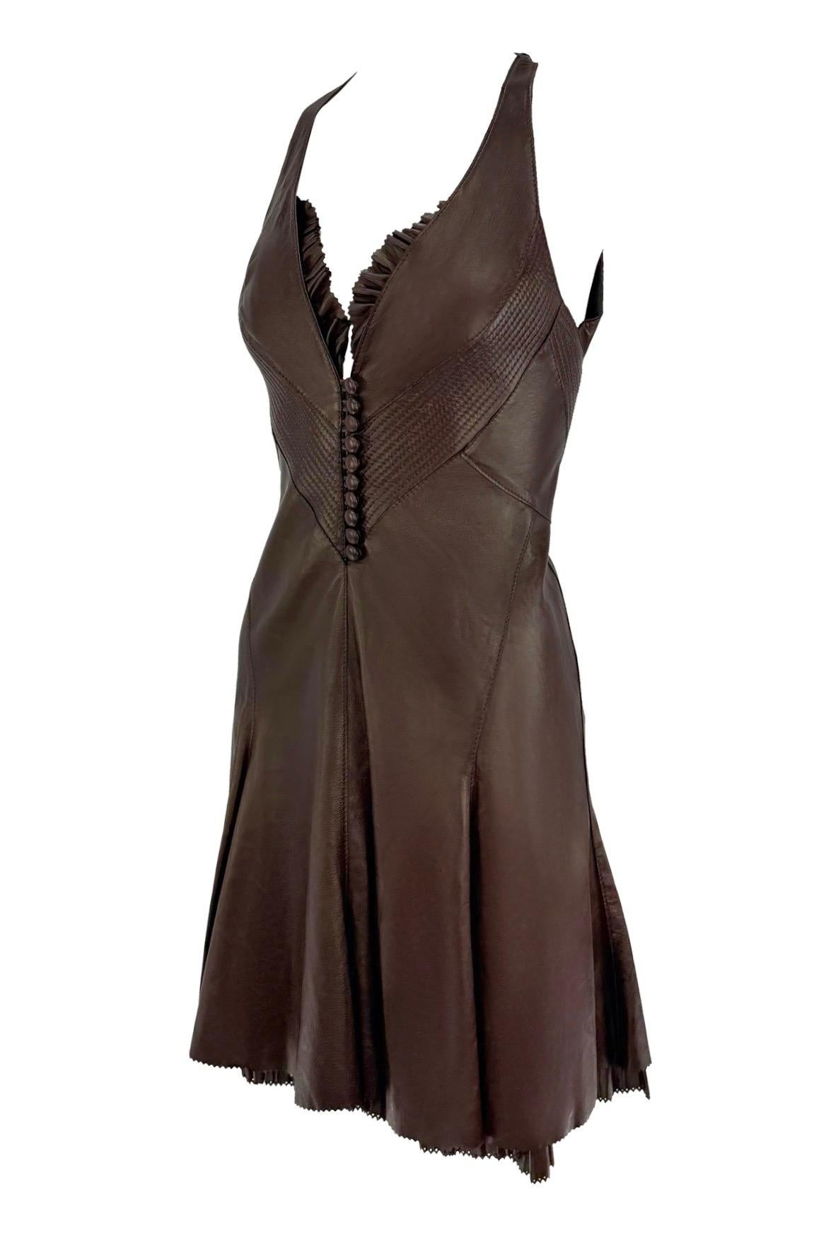 From Roberto Cavalli’s 2004 collection, this new-with-tags mini dress is crafted from supple chocolate brown leather. Featuring a plunging halter neckline trimmed with ruffles, a structured bodice with covered buttons, and a flared hemline, the