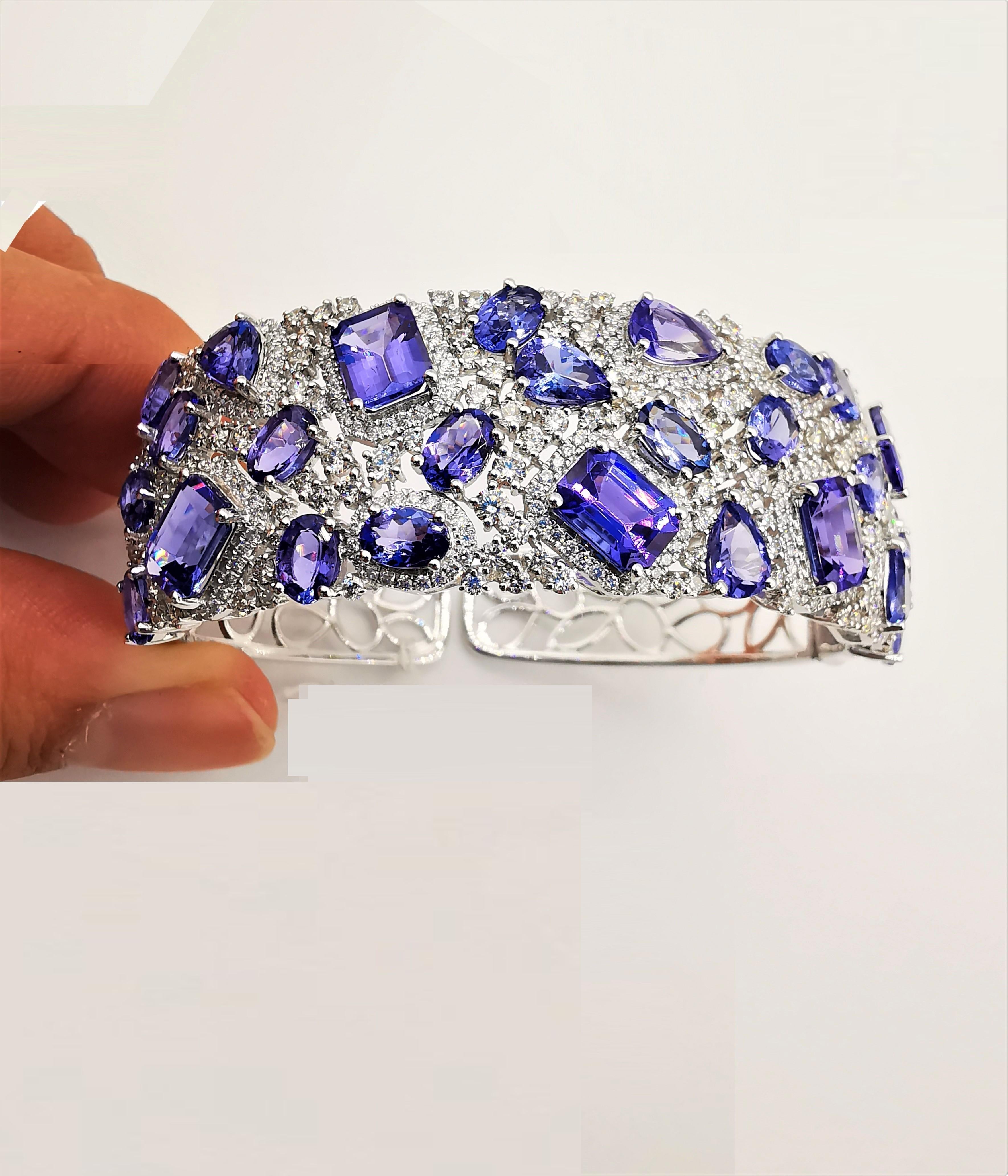 The Following Item we are offering is a Rare Important Radiant 18KT Gold Large Magnificent Rare Fancy Gorgeous Fancy Cut Tanzanites and Diamond Bangle Bracelet. Bangle is comprised of Exquisite Fancy Oval Cut Intense Rich Tanzanites connected with