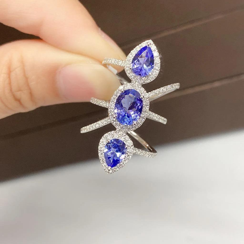 L'article suivant que nous proposons est une bague en or 18KT rare, importante et rayonnante, avec une Tanzanite et un diamant. La bague est composée de trois magnifiques Tanzanites de taille assortie, d'une richesse intense, entourées d'un halo de