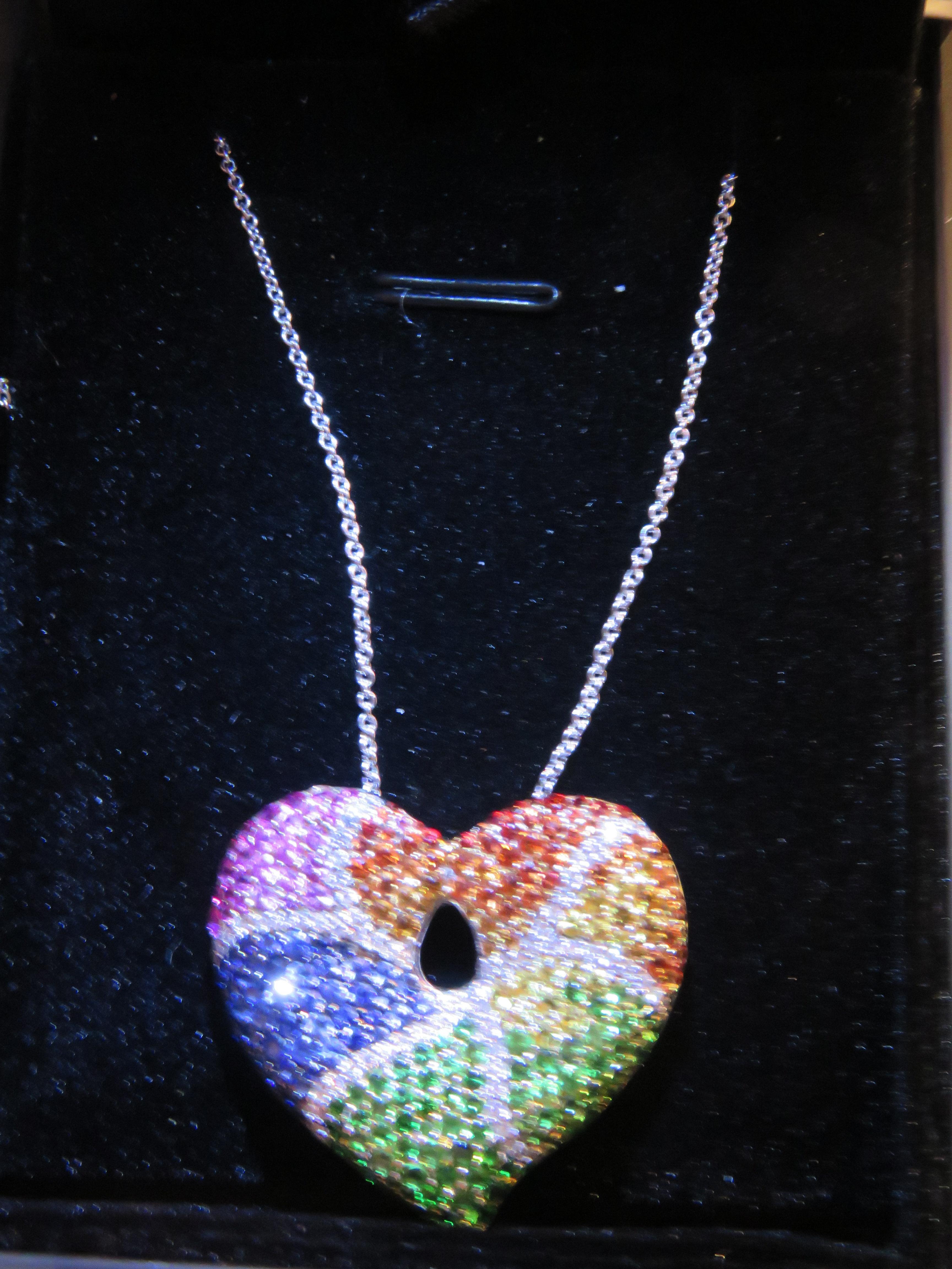 The Following Item we are offering is this Beautiful Rare Important 18KT White Gold Black Diamond, Ruby, Pink, Orange, Yellow, Blue Sapphire and Green Tsavorite Heart Pendant Necklace. Necklace is comprised of over 4 Carats of Fine Invisibly Set