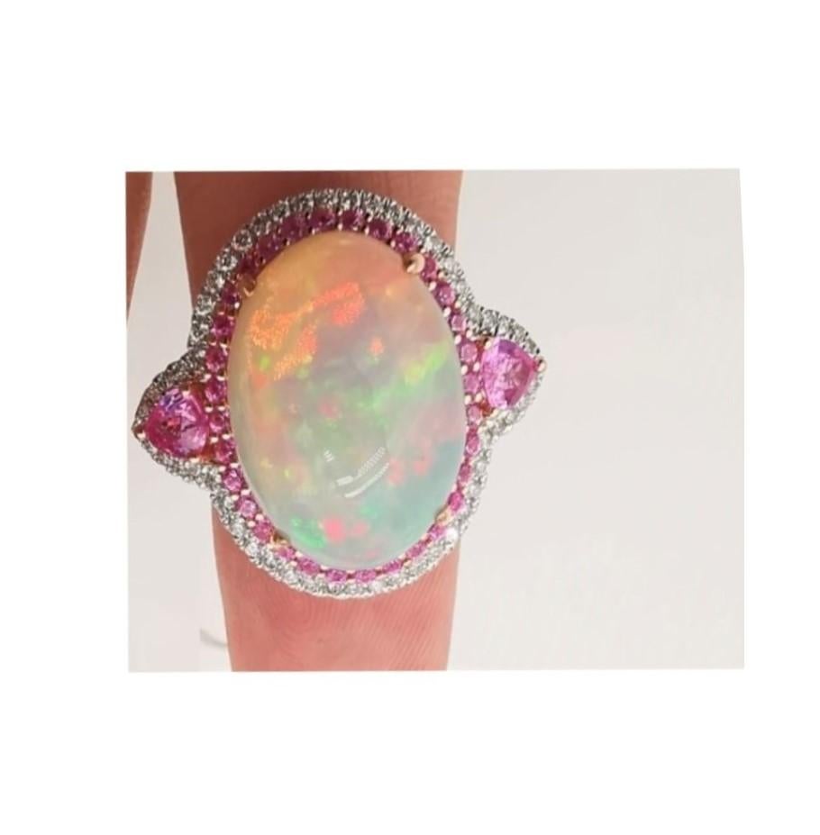The Following Item we are offering is a Rare Important Radiant 18KT Gold Large Fancy Fiery White Opal Diamond Pink Sapphire Ring. Ring is comprised of A LARGE Gorgeous Fancy Fiery White Rainbow Opal surrounded by a Beautiful Halo of Glittering
