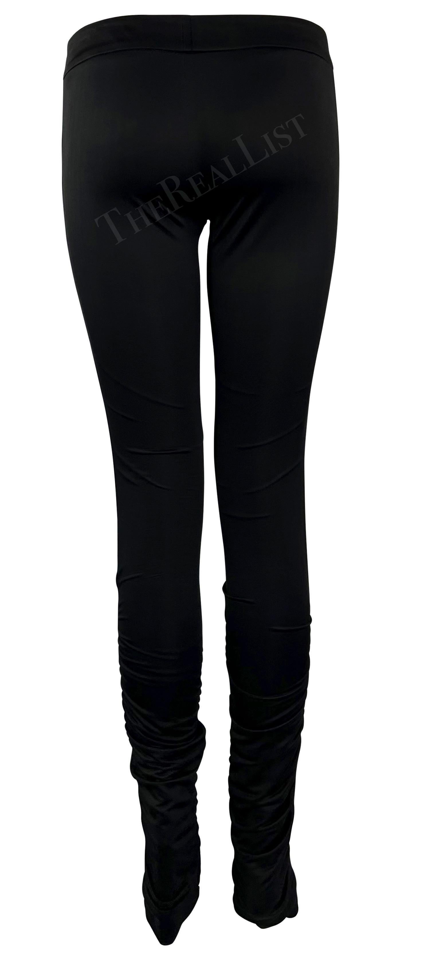 Te presentamos unos pantalones negros de Gucci, diseñados por Tom Ford. De la colección Otoño/Invierno 2004, estos pantalones de satén ajustados presentan fruncidos en las pantorrillas y se completan con una cinta de rayas monocromática a cada lado.